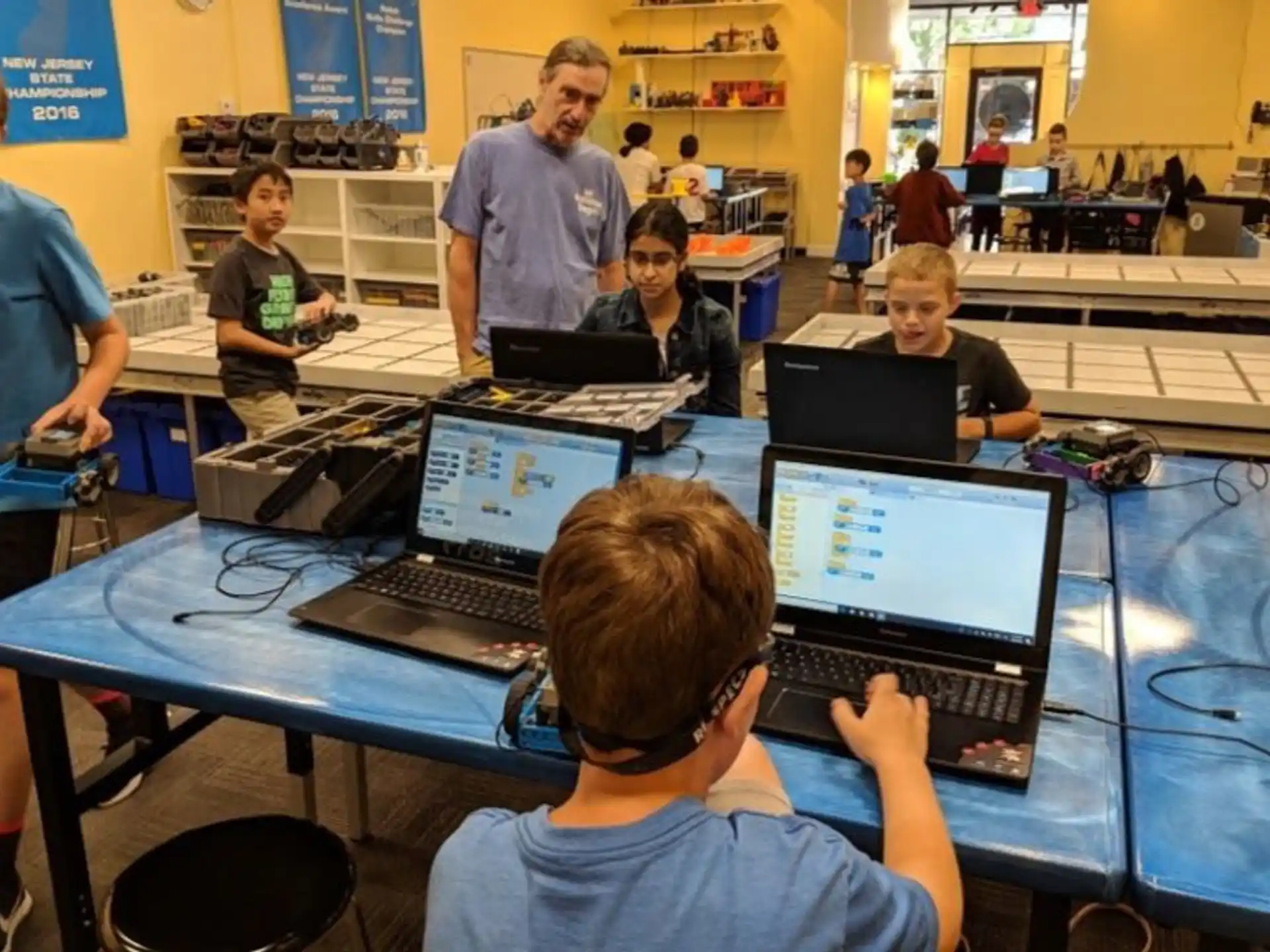 a group of people sitting at a table with laptops