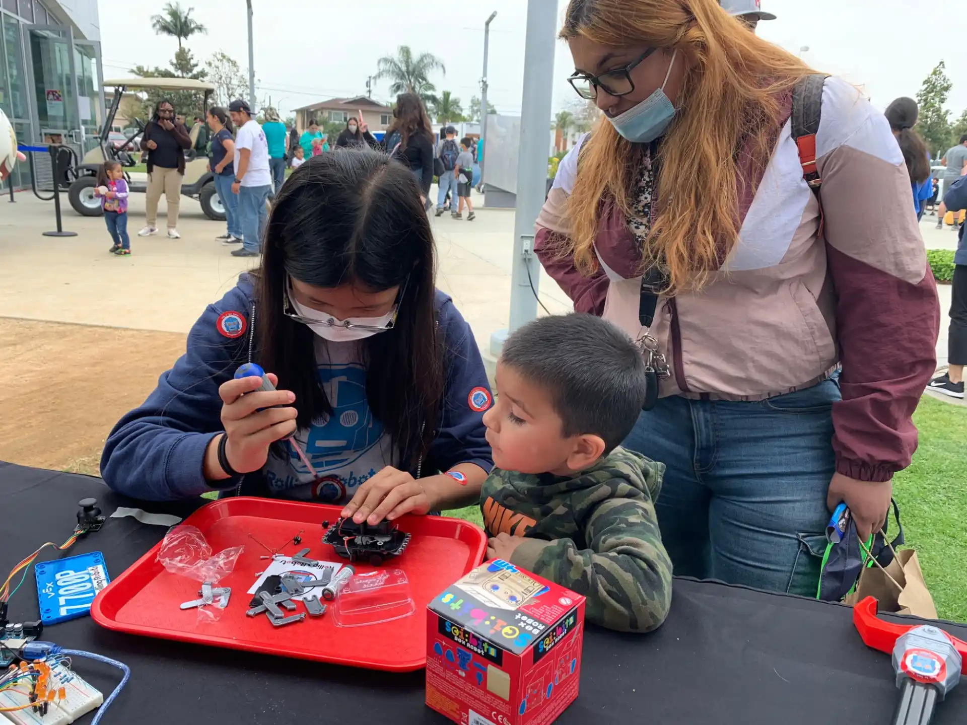 a person and two children playing with toys on the ground