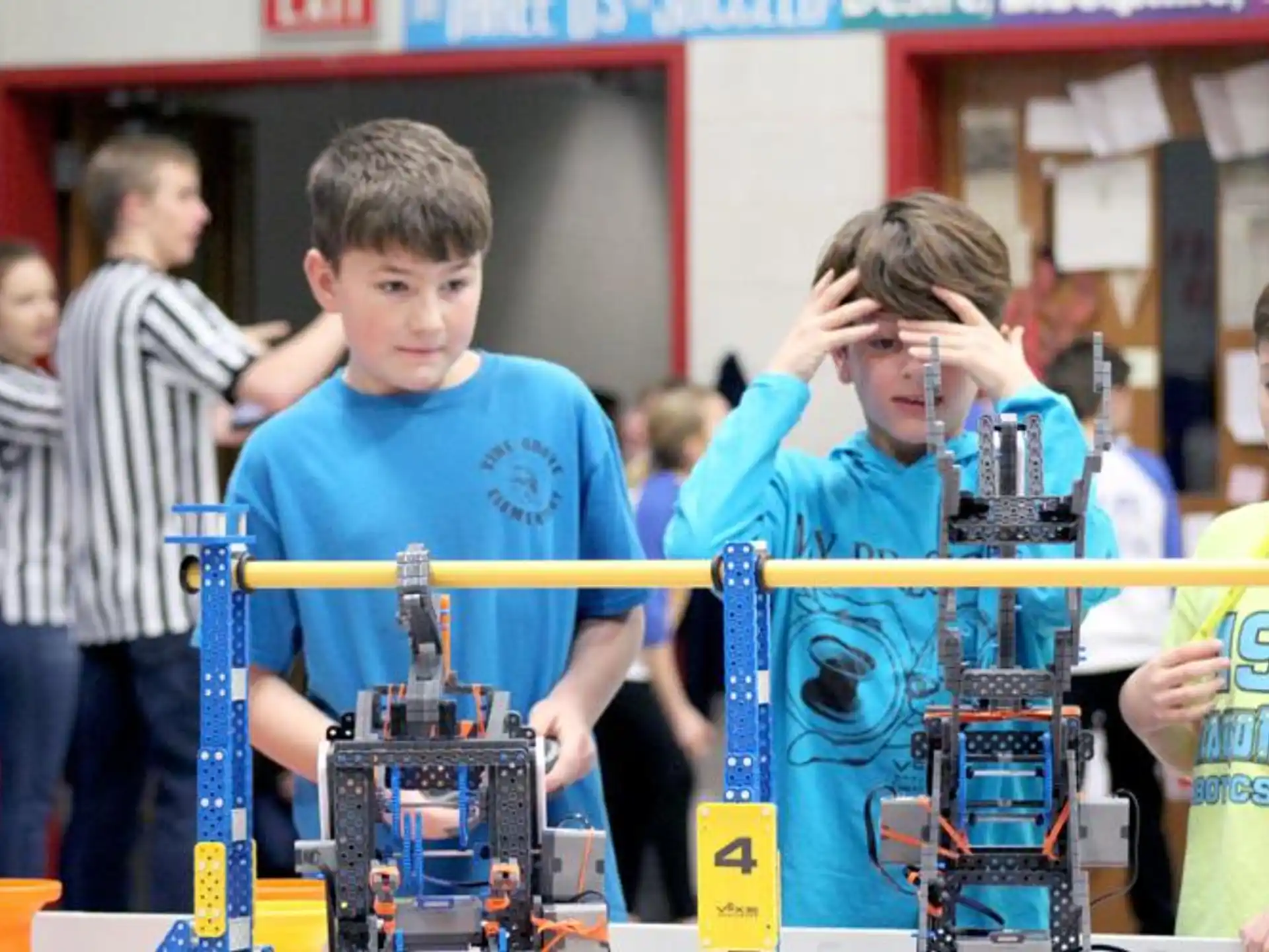 a group of kids standing around a table with a robot