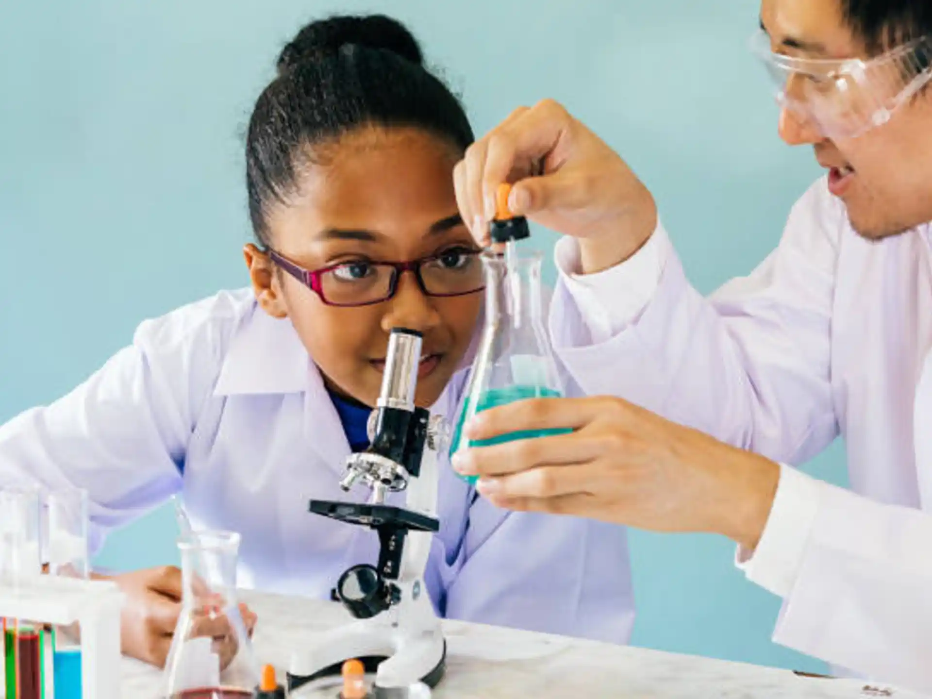 a few men in lab coats looking at a microscope