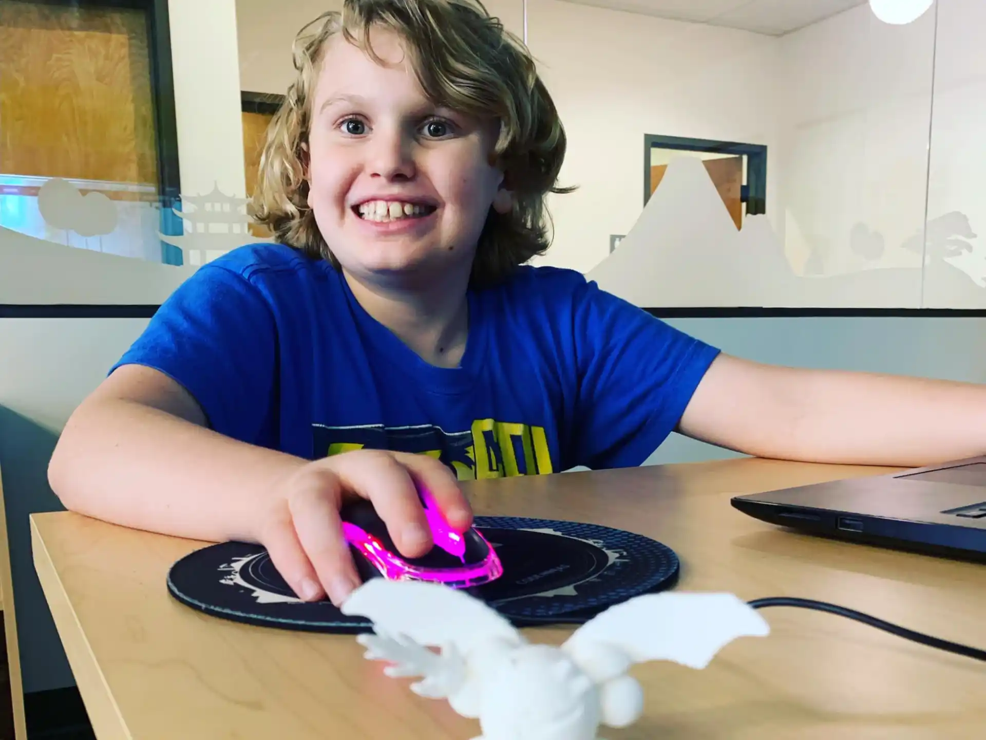 a boy sitting at a table with a mouse and a toy