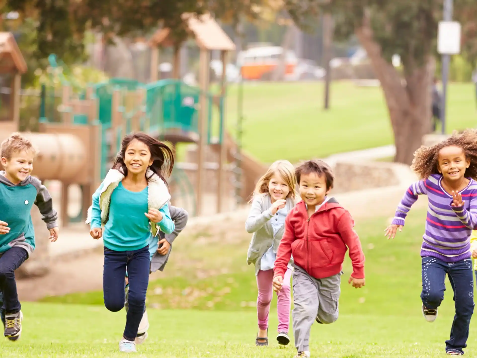 a group of children running on a grass field