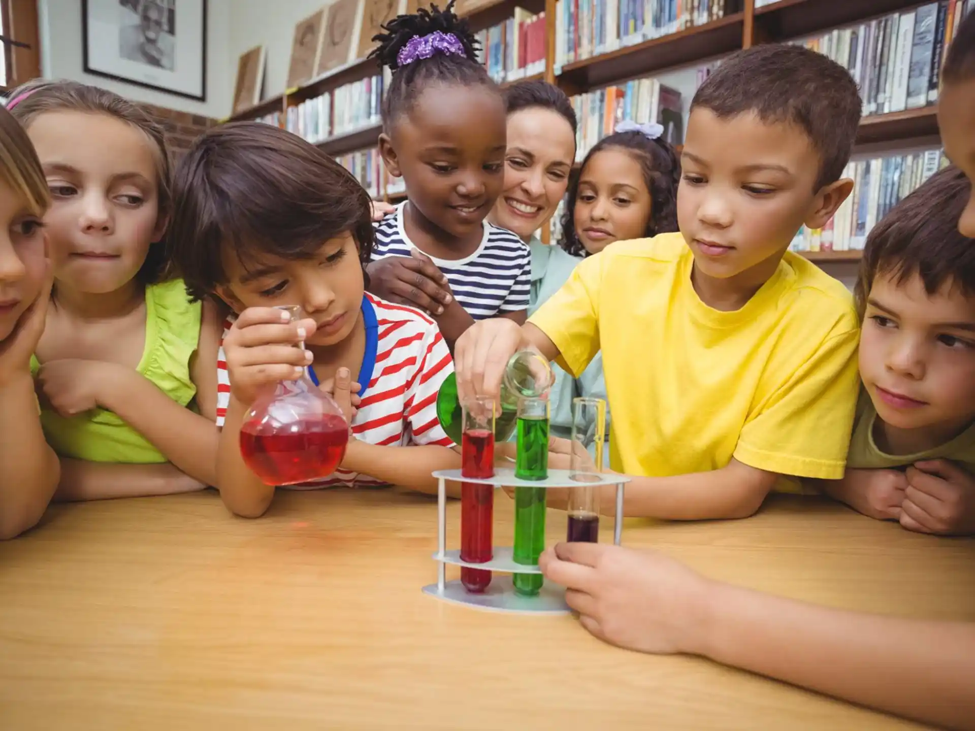 a group of children sitting at a table with a glass of liquid