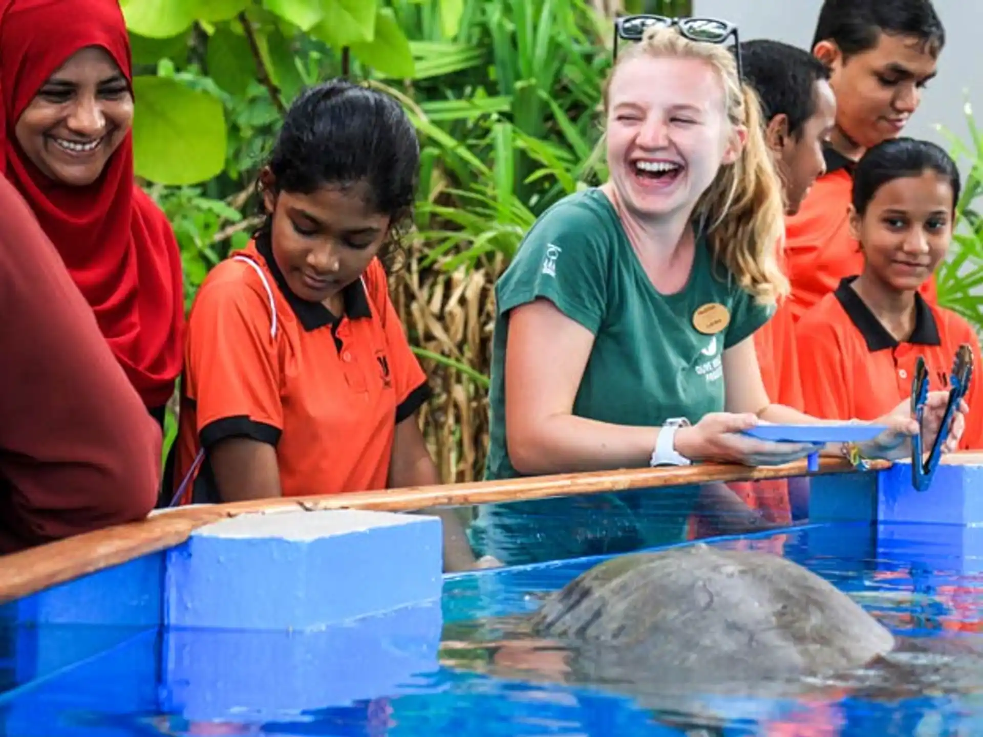 a group of people looking at a fish in a pool