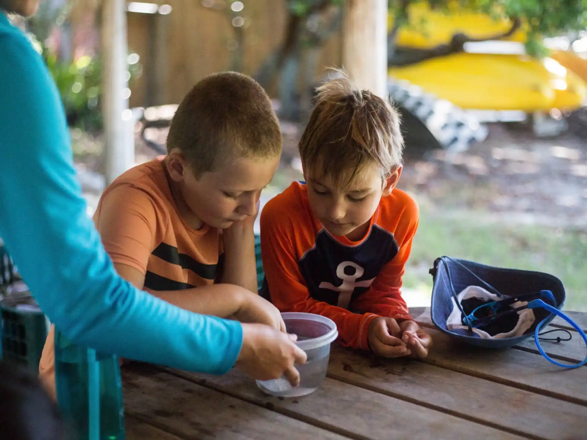a couple of boys sitting at a table looking at a cup