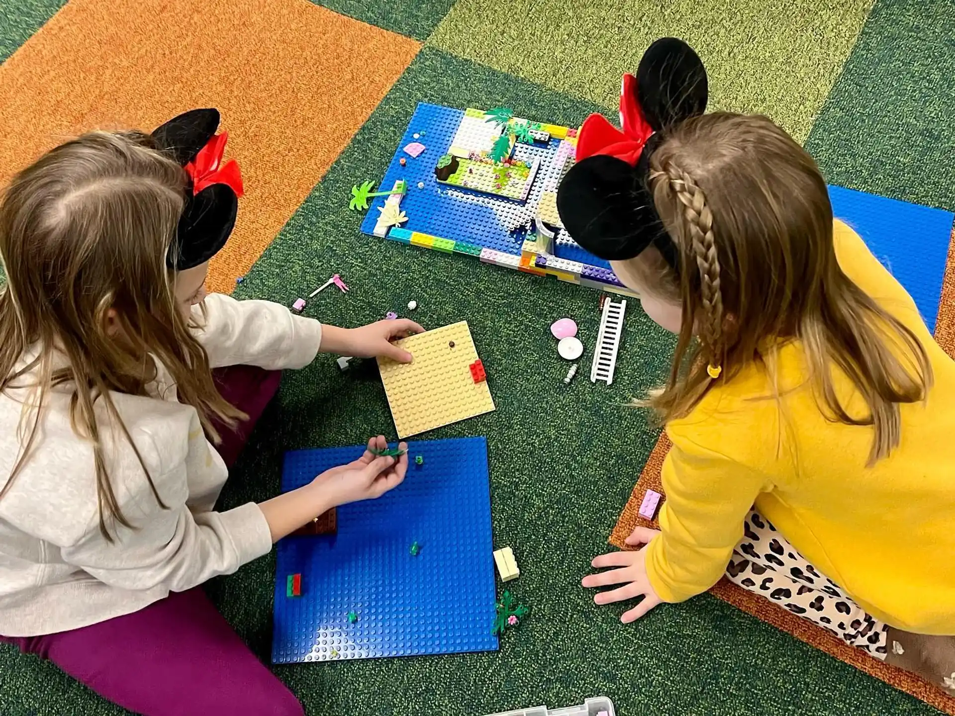 a few young girls playing with colorful paper on the floor