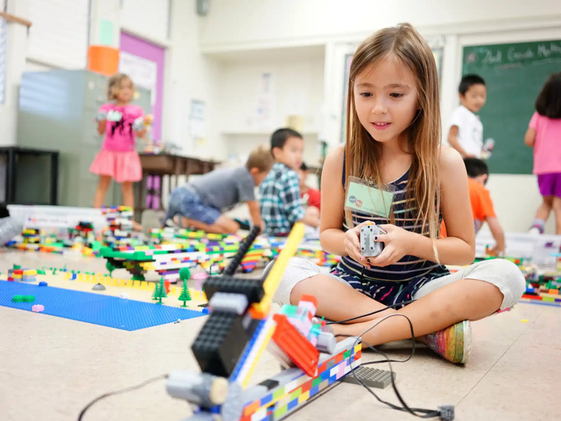a girl sitting on the floor with a toy train and other children