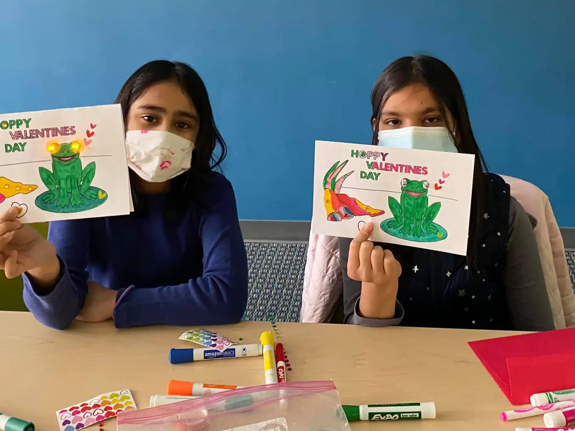 a couple of girls holding up drawings