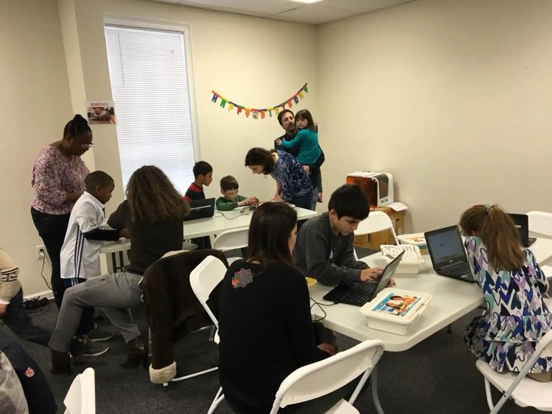 a group of people sitting around a table with laptops
