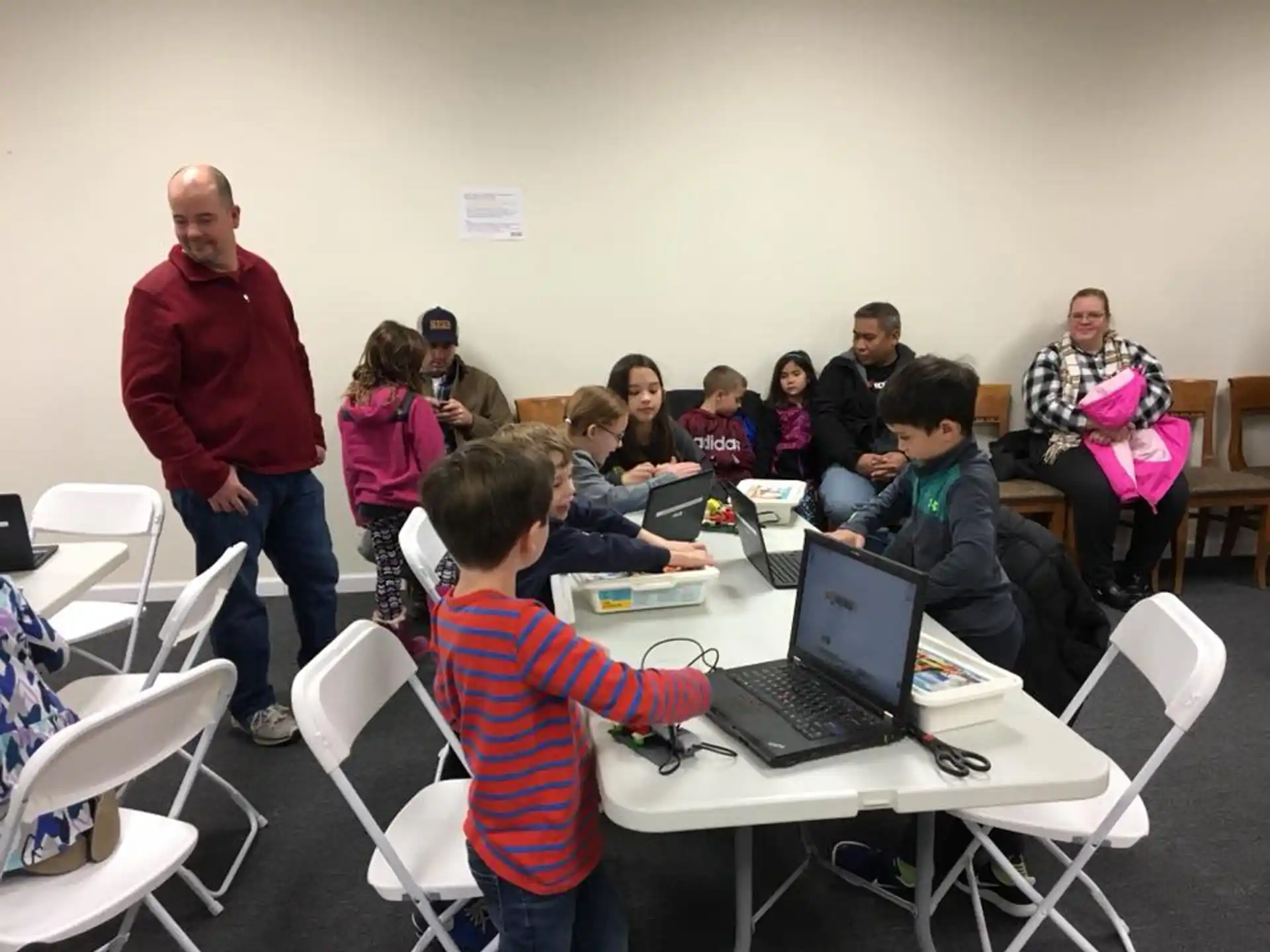 a group of people sitting at tables with laptops