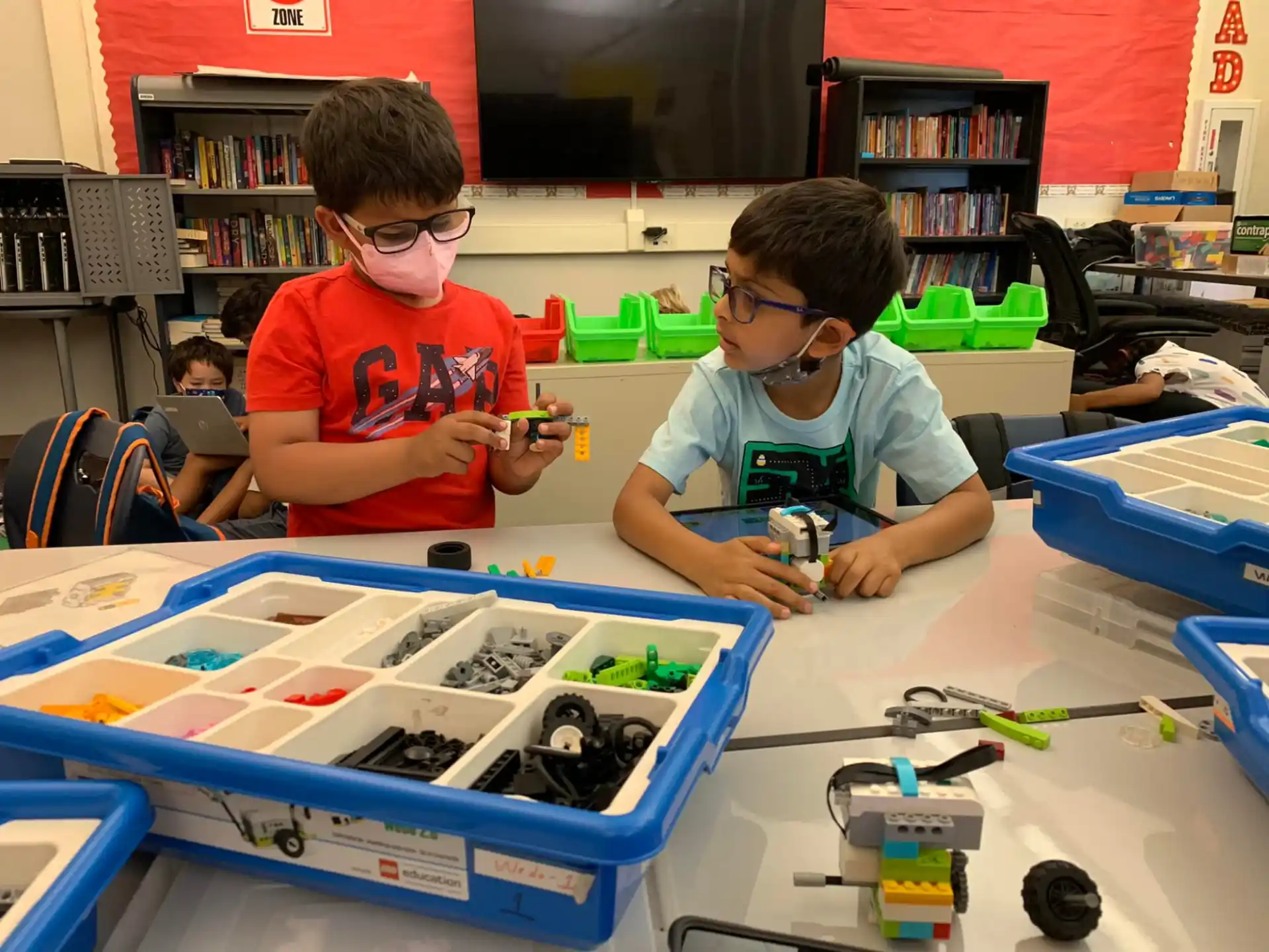 a couple of boys wearing safety goggles and looking at a blue object