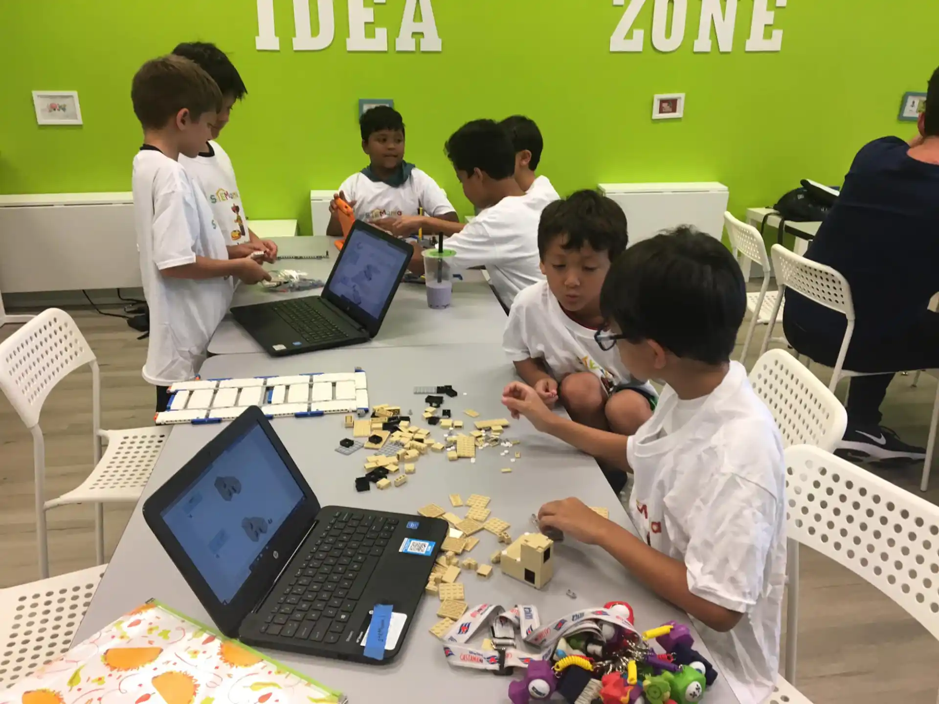 a group of boys sitting at a table with laptops
