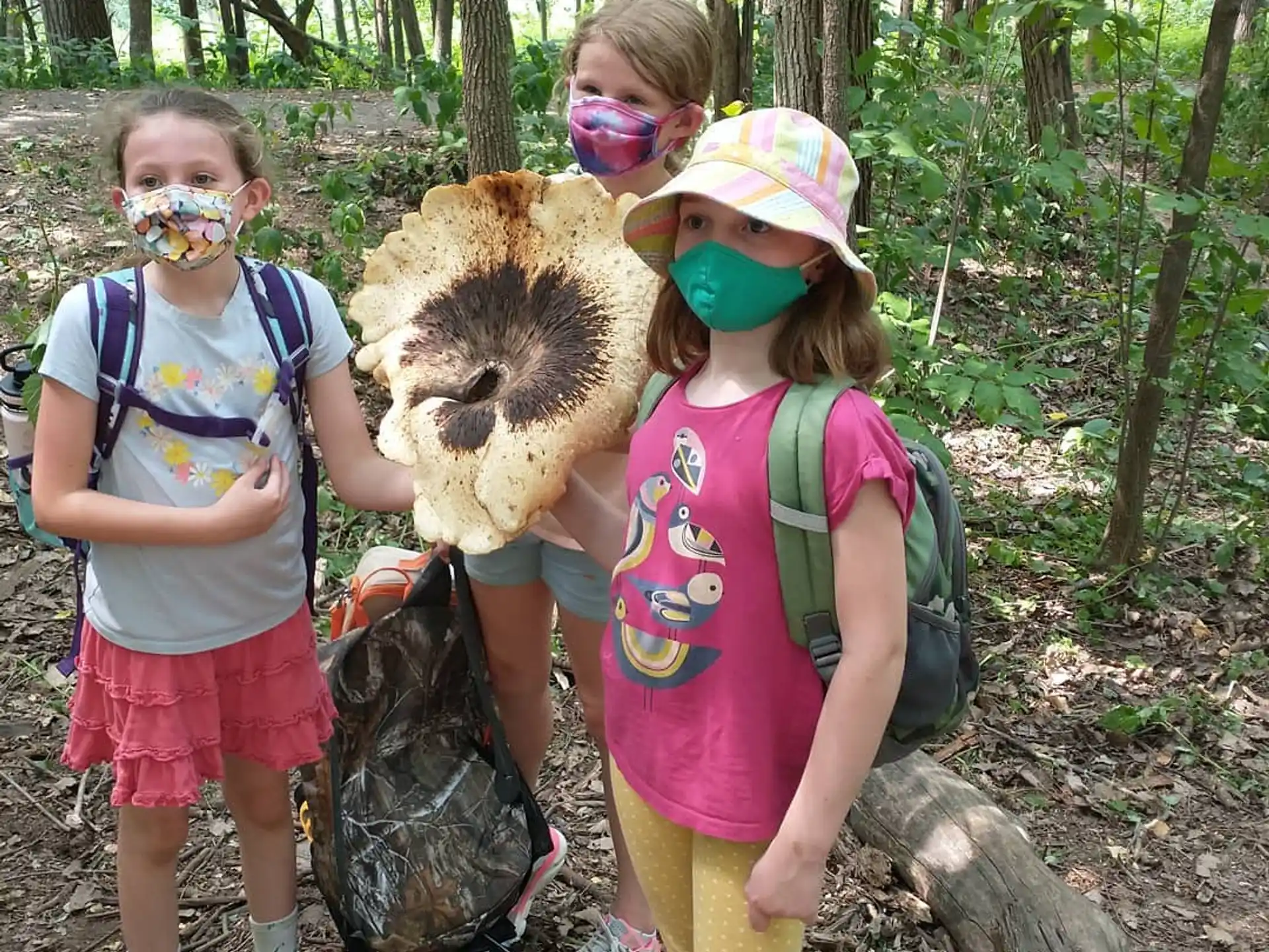 a group of girls with backpacks and a bear in the woods