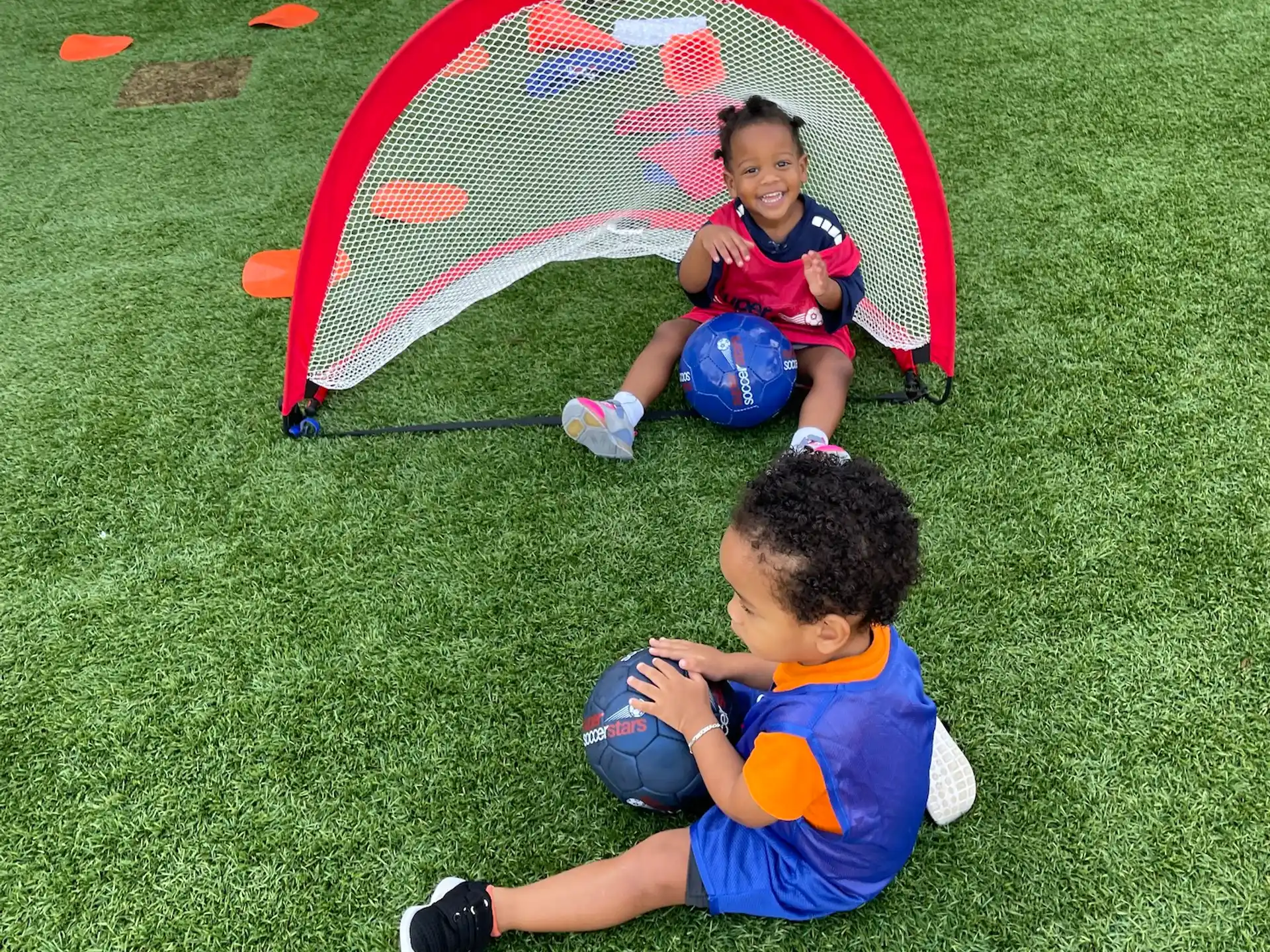 a couple of kids playing with a ball in a grassy area