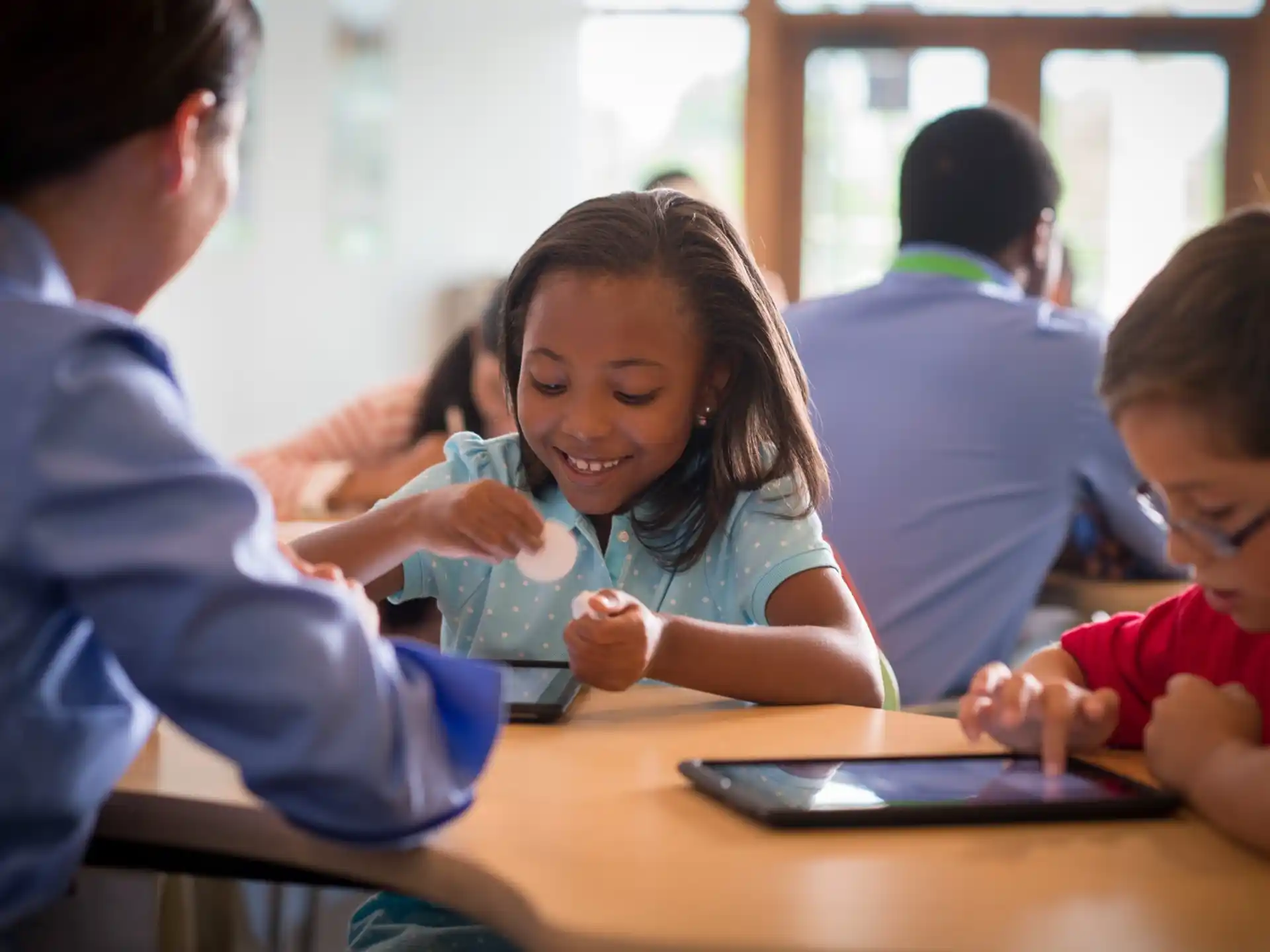 a group of people sitting at a table looking at a tablet