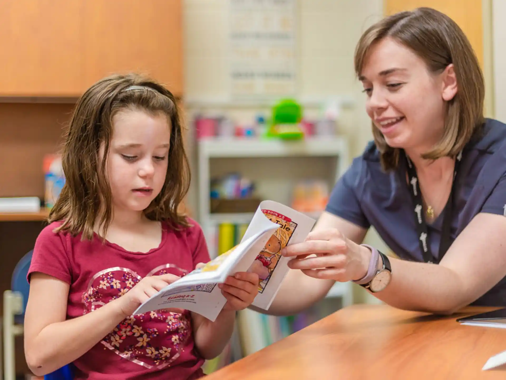 a person reading a book to a young girl