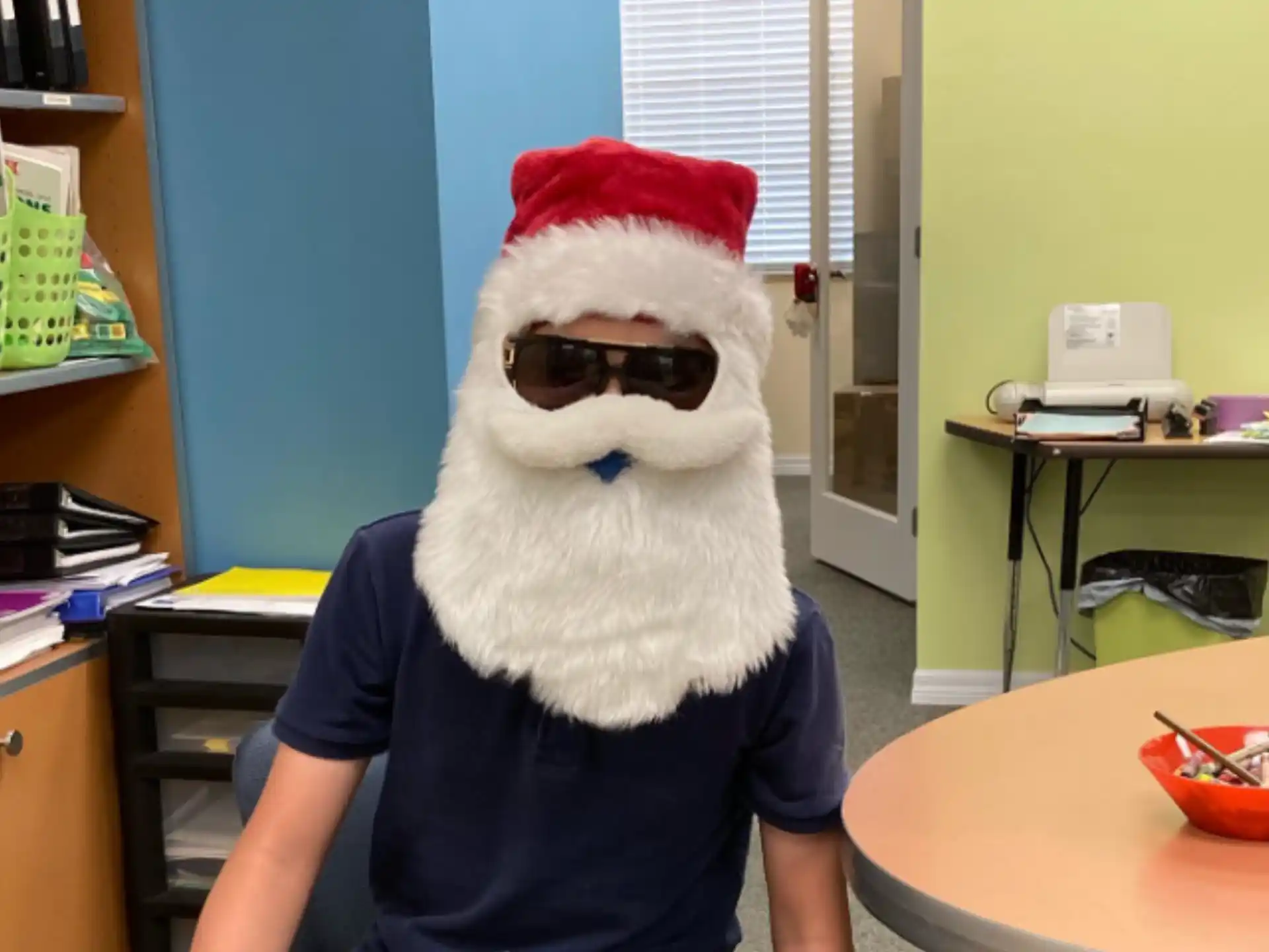 a person wearing a santa hat and sunglasses sitting at a desk