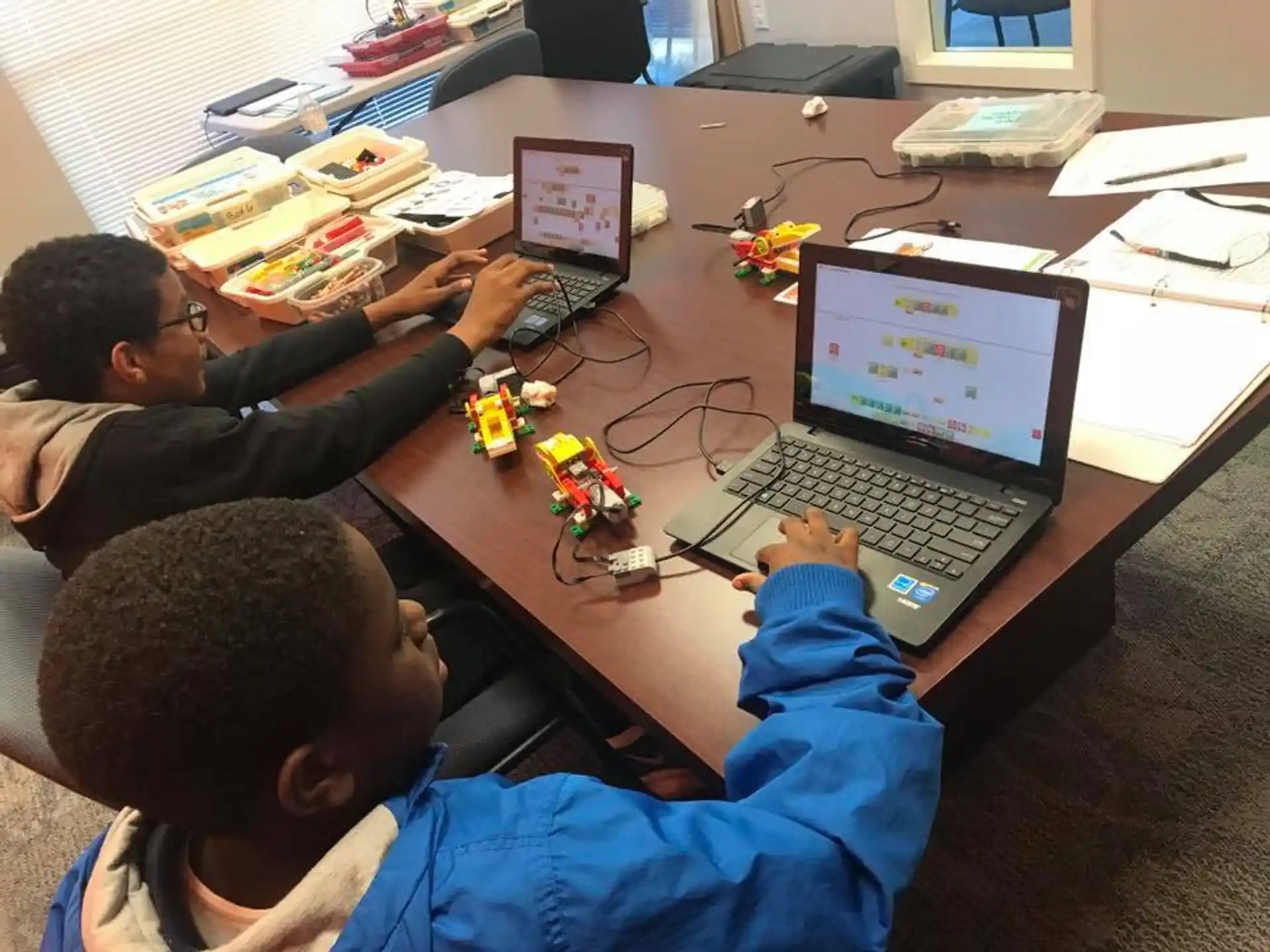 a group of people sitting at a table with laptops