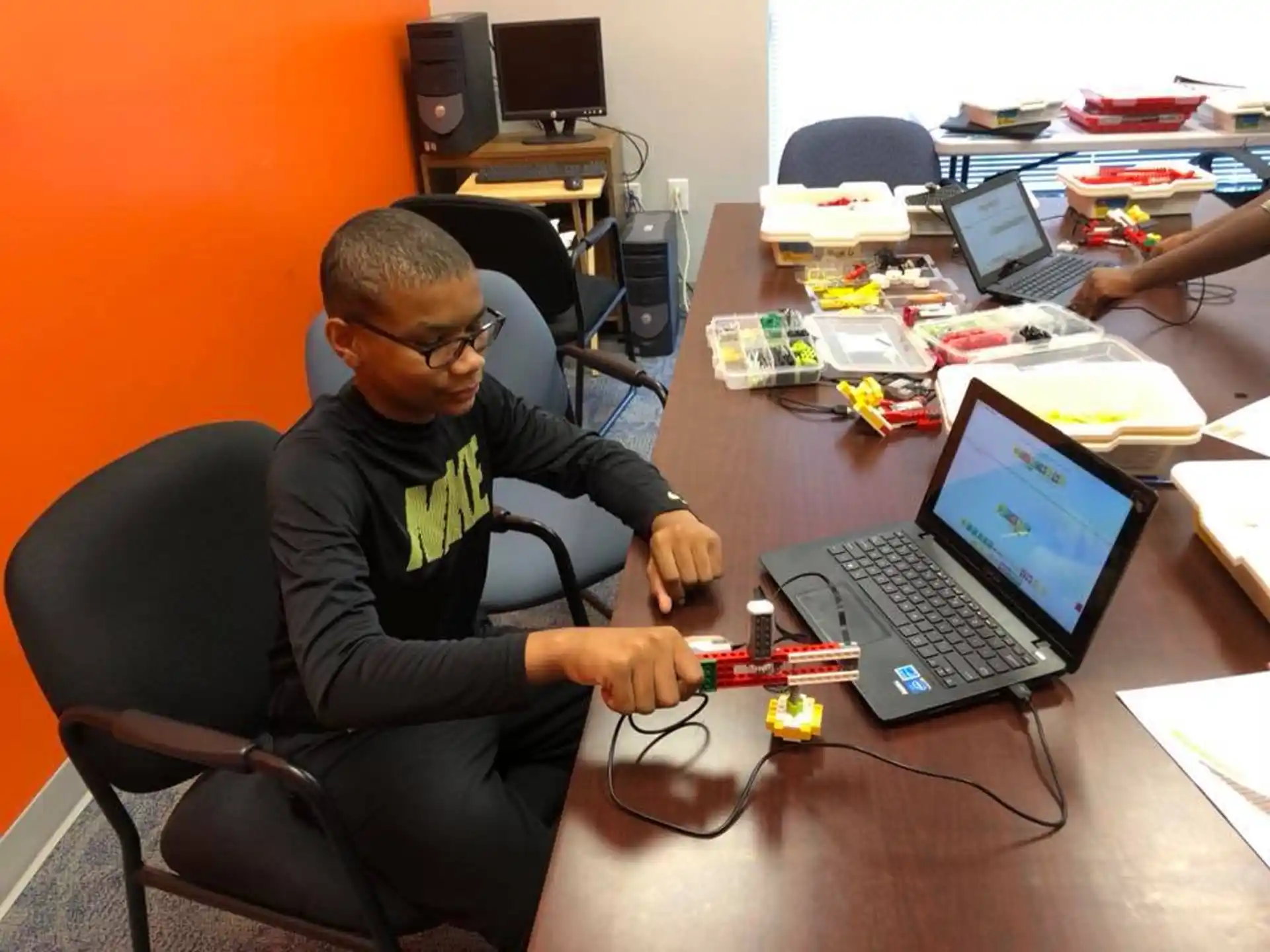 a person sitting at a desk with a laptop and other computers