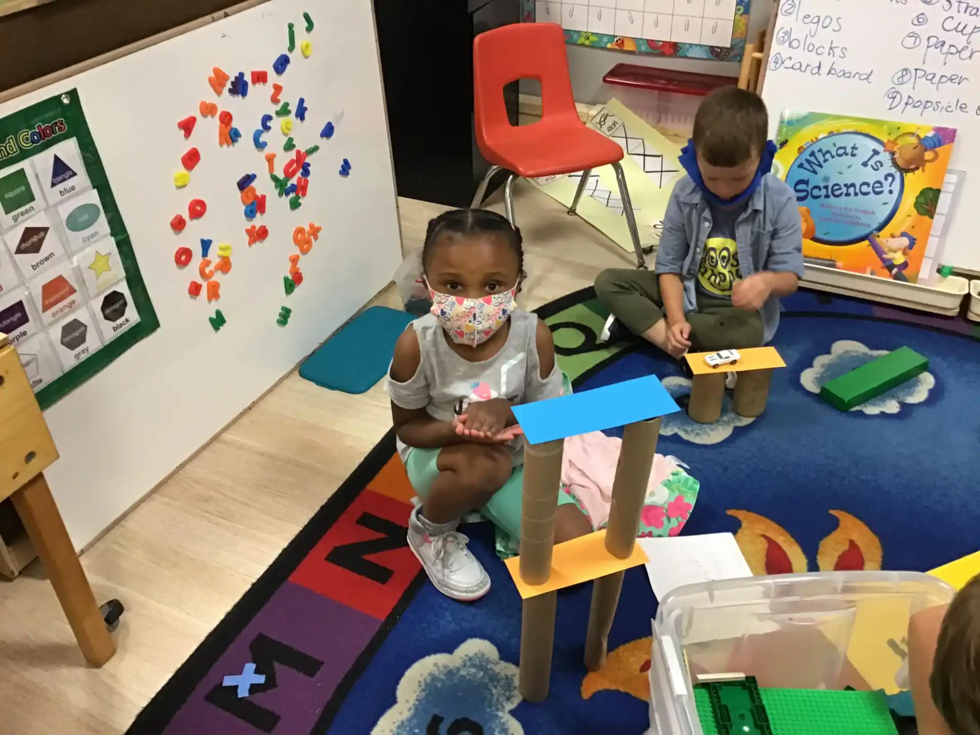 a boy and a girl sitting at a table with toys