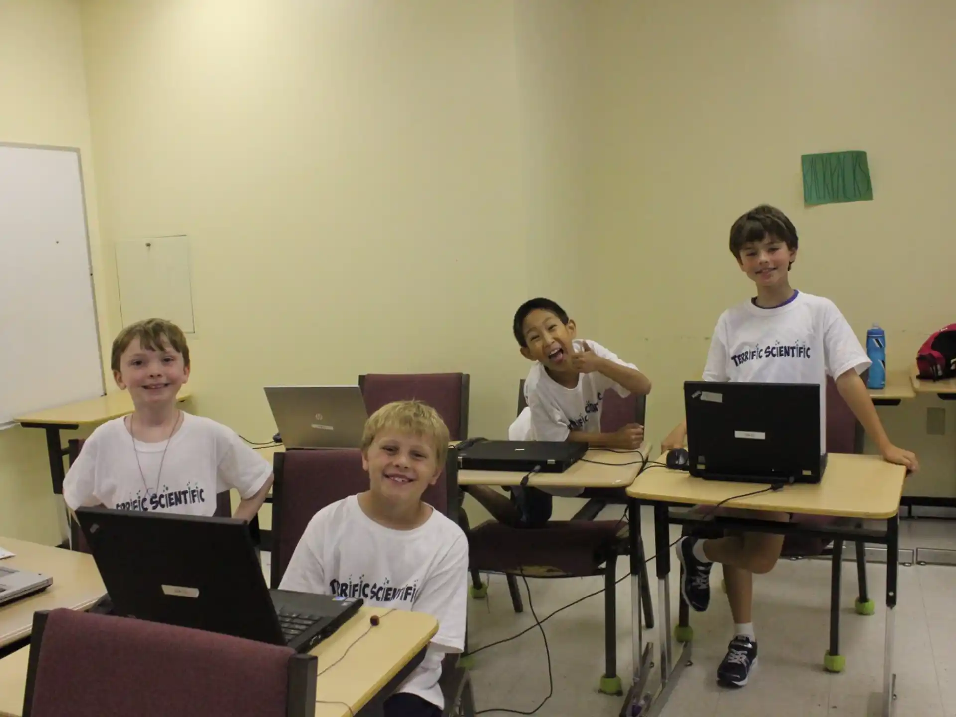 a group of boys sitting at desks with laptops