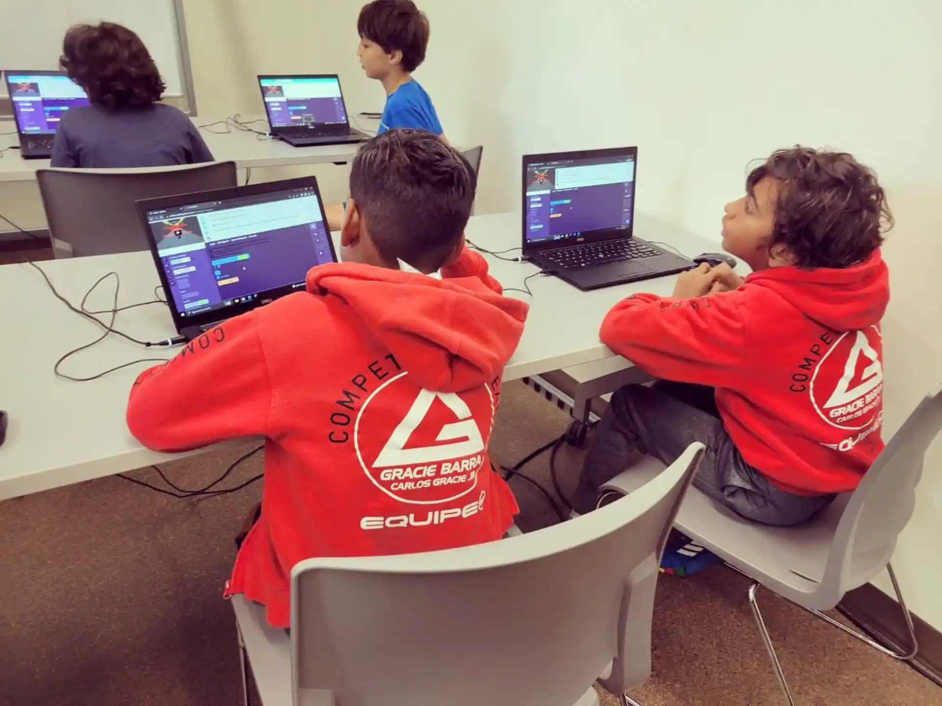 a group of people sitting at a table with laptops