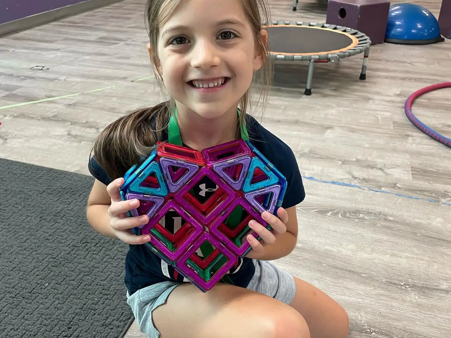 a girl sitting on the floor holding a toy