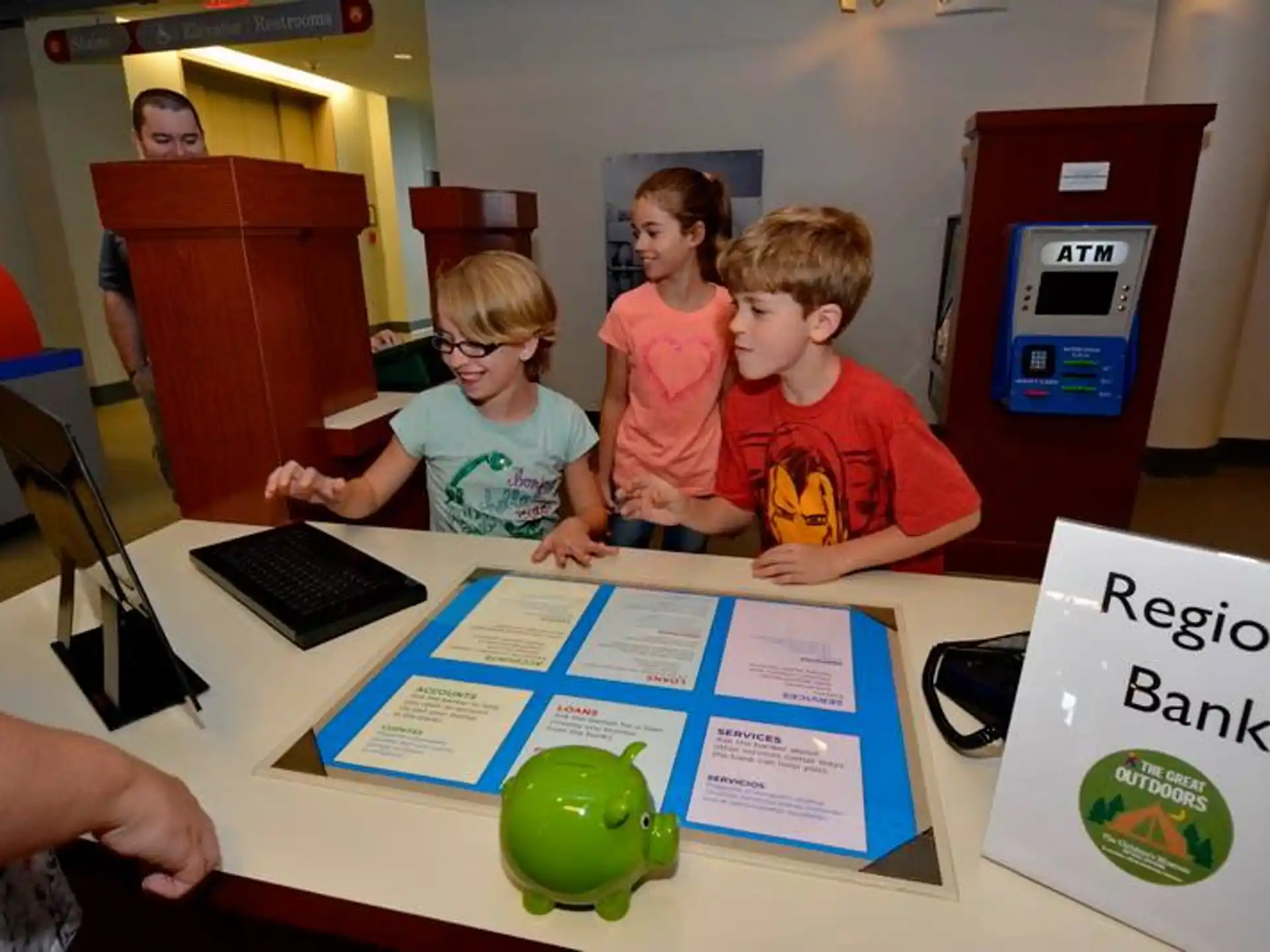 a group of children sitting at a table with a computer and a game