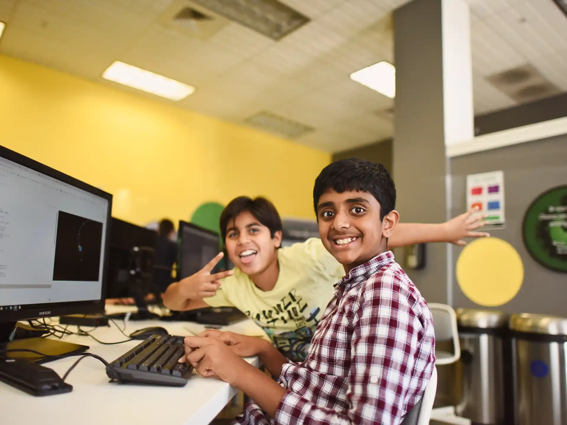 a couple of boys sitting at a computer desk