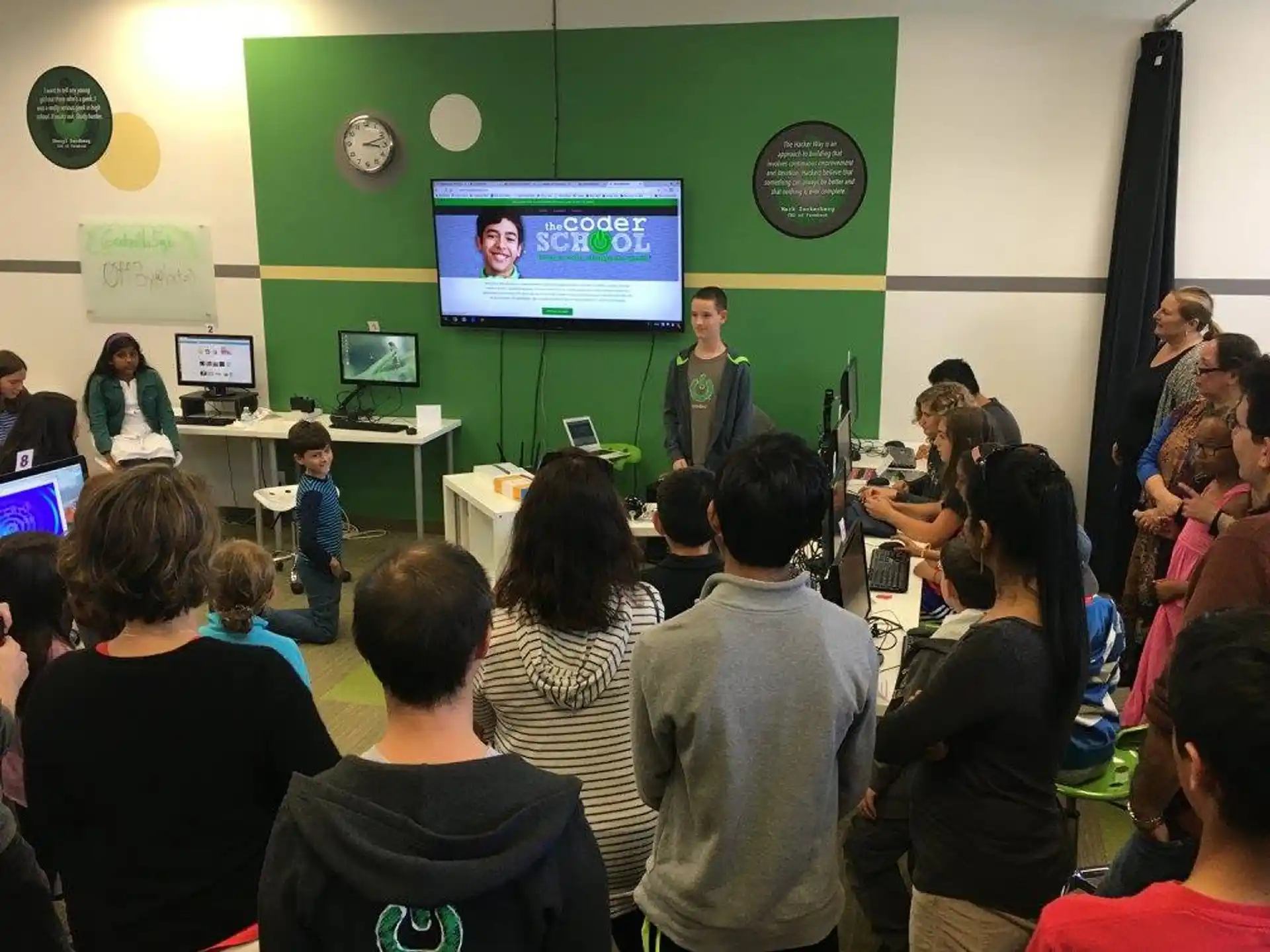 a group of people watching a person on a screen
