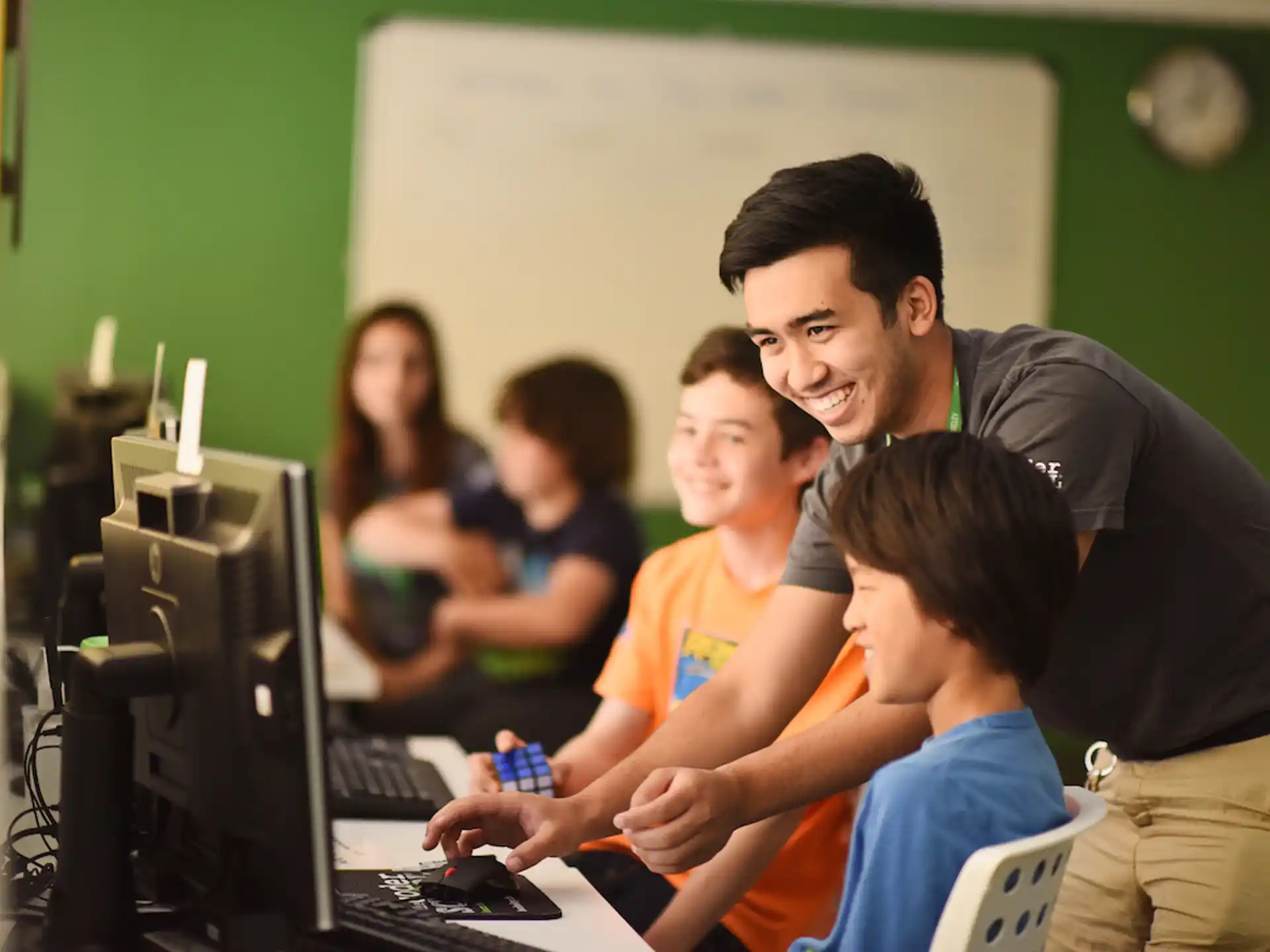 a person showing a group of kids something on the computer