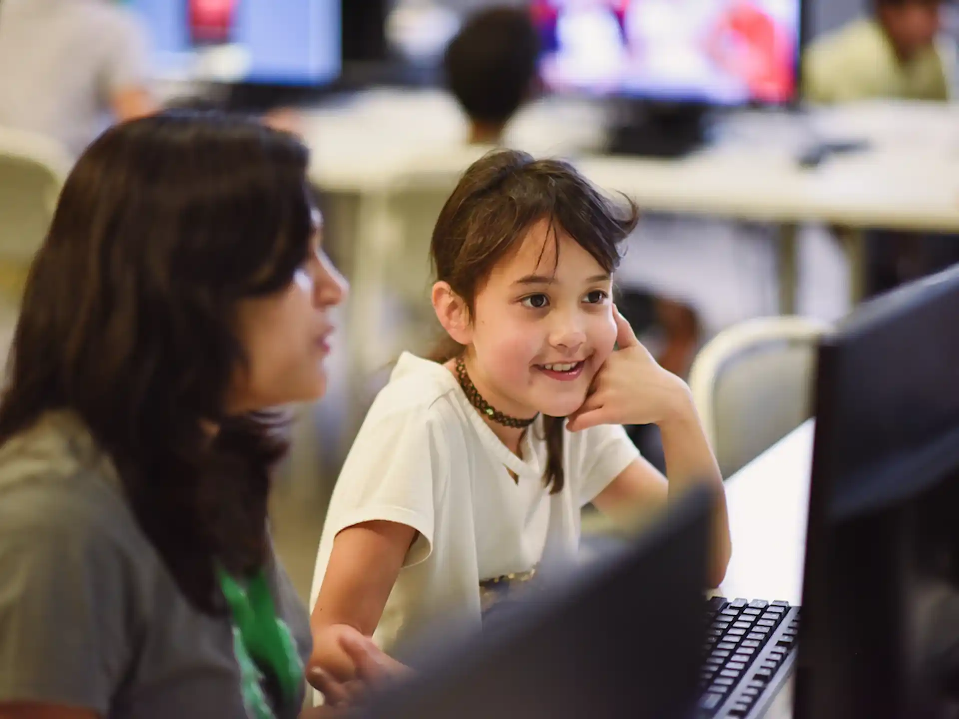 a woman and a child looking at a computer screen