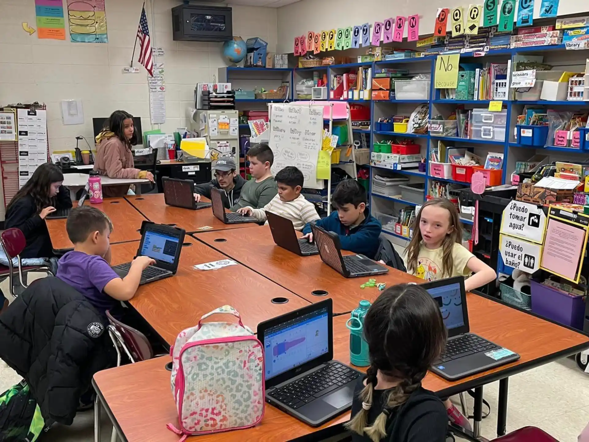 a group of people sitting at a table with laptops