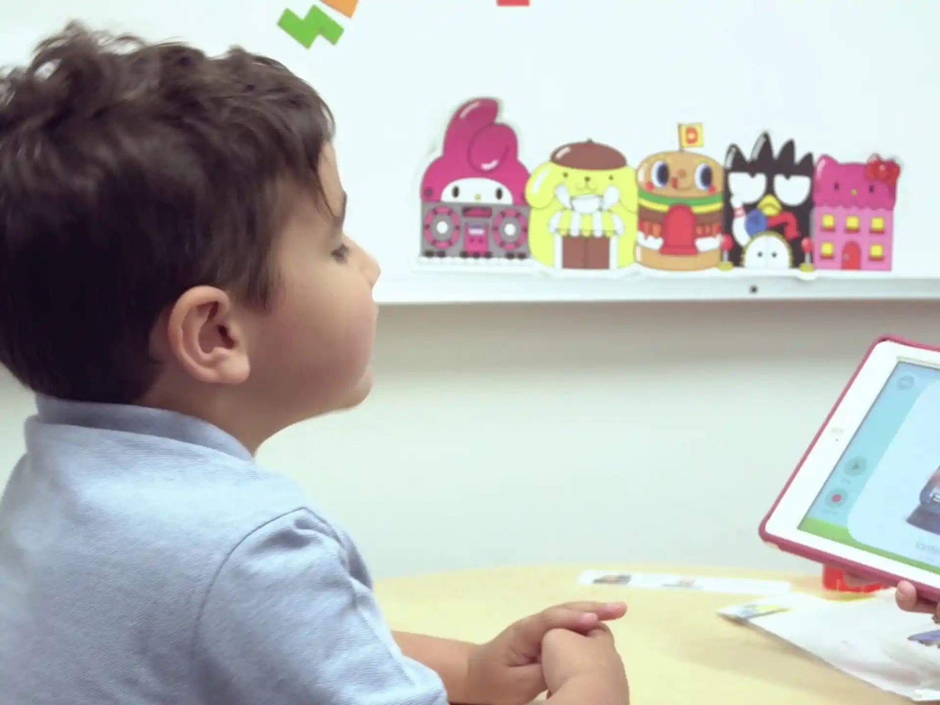 a child sitting at a table looking at a tablet