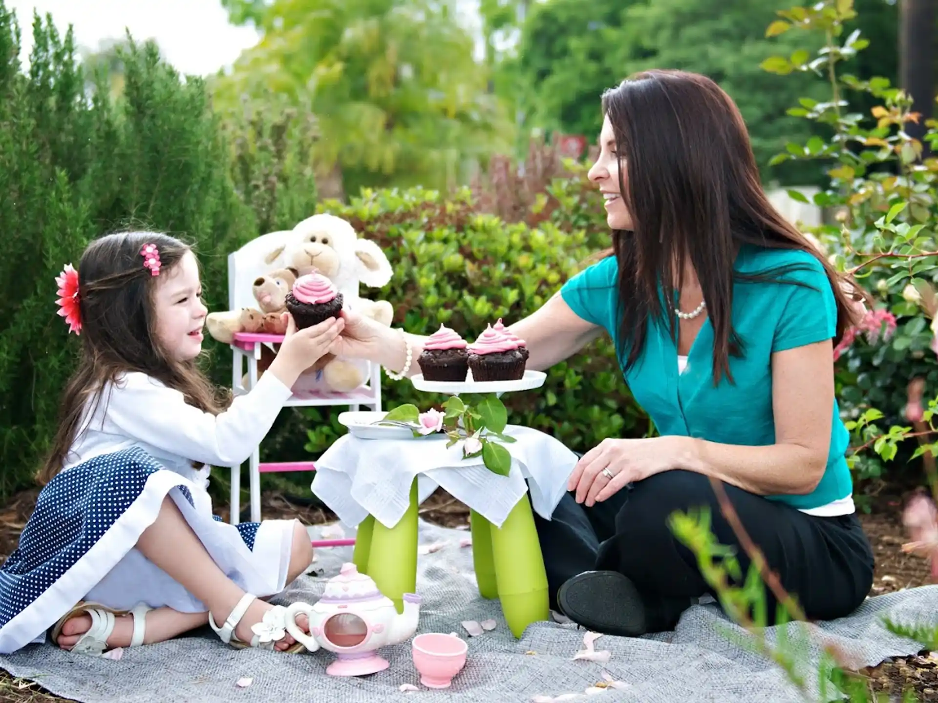 a woman and a girl sitting on a bench with a teddy bear