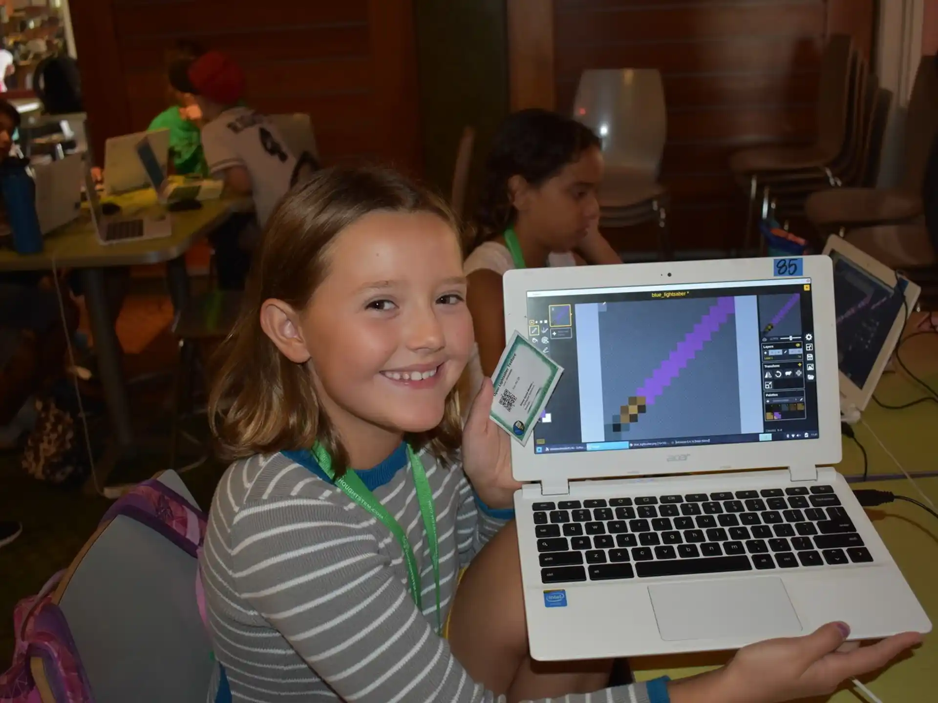 a young girl smiling while holding a laptop