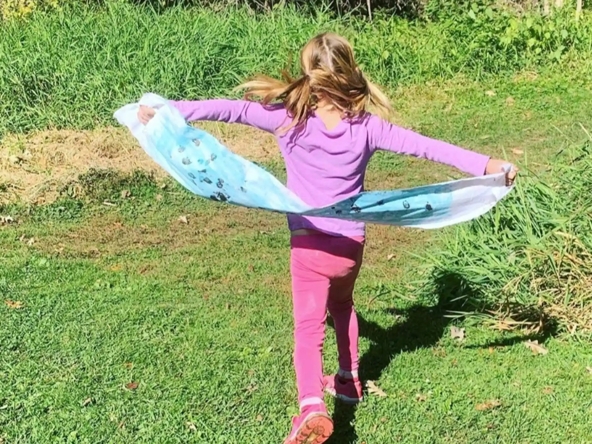 a girl holding a blue and purple tube in a grassy area