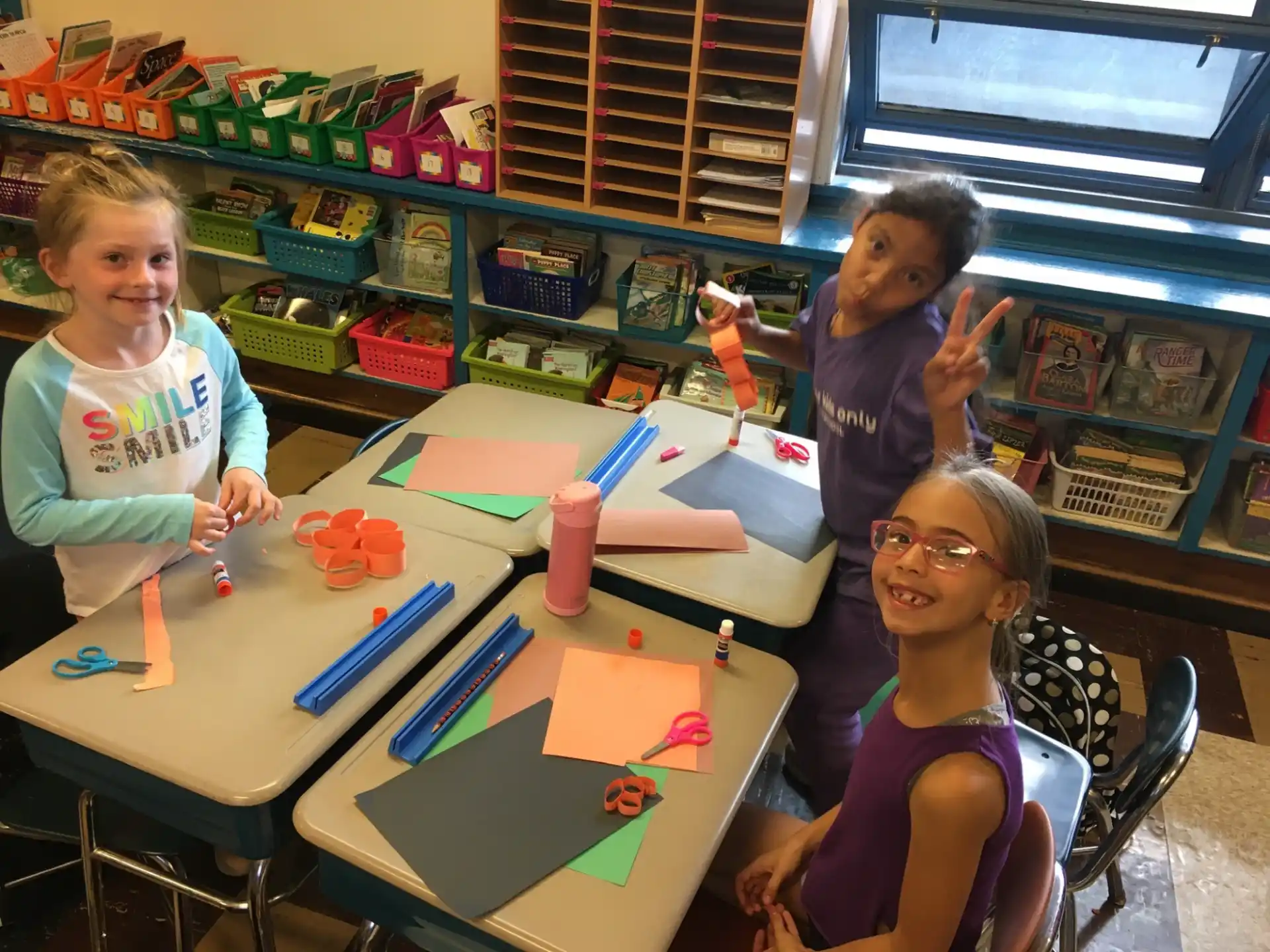 a group of children sitting at a table with colorful paper on it