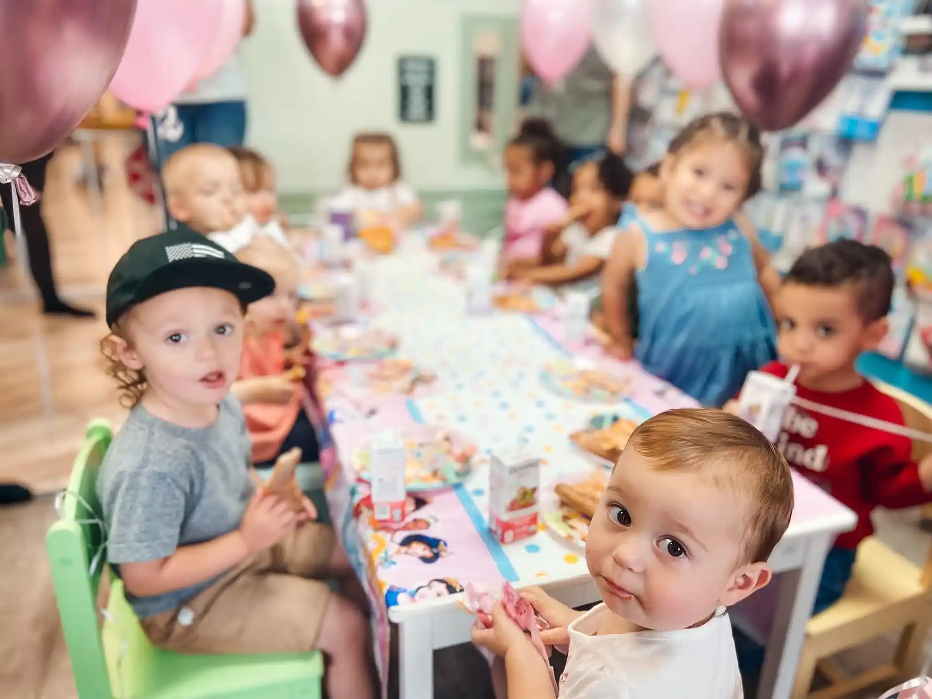 a group of children sitting around a table with balloons