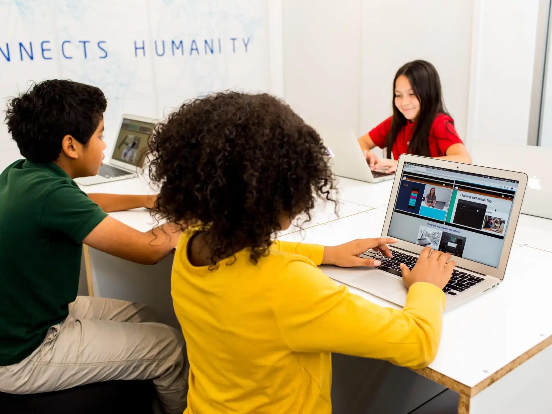 a group of people sitting at a table looking at a laptop