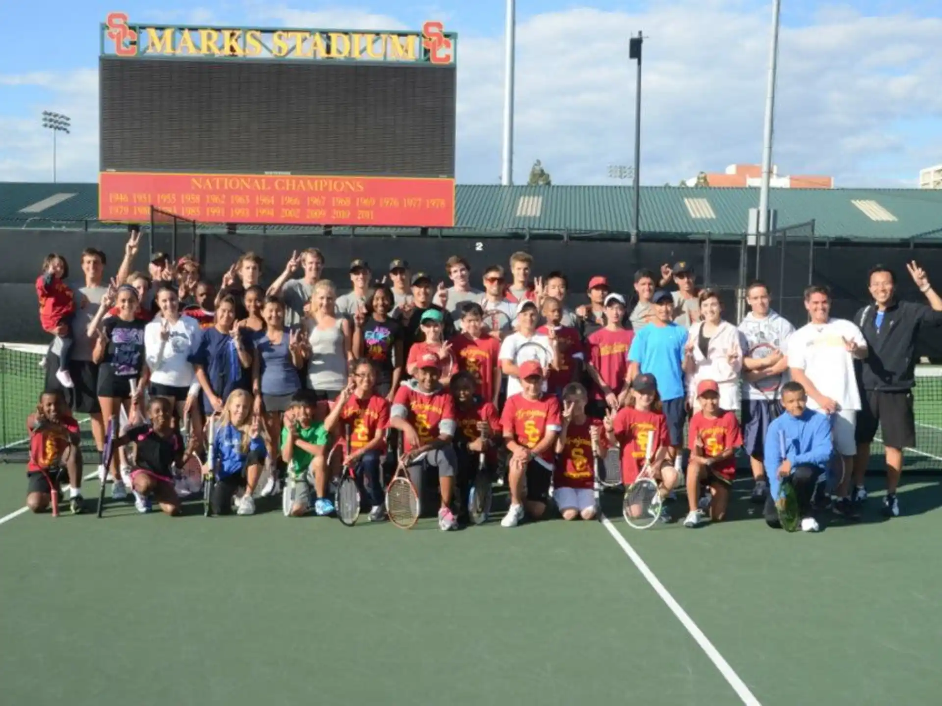 a group of people posing for a photo on a tennis court