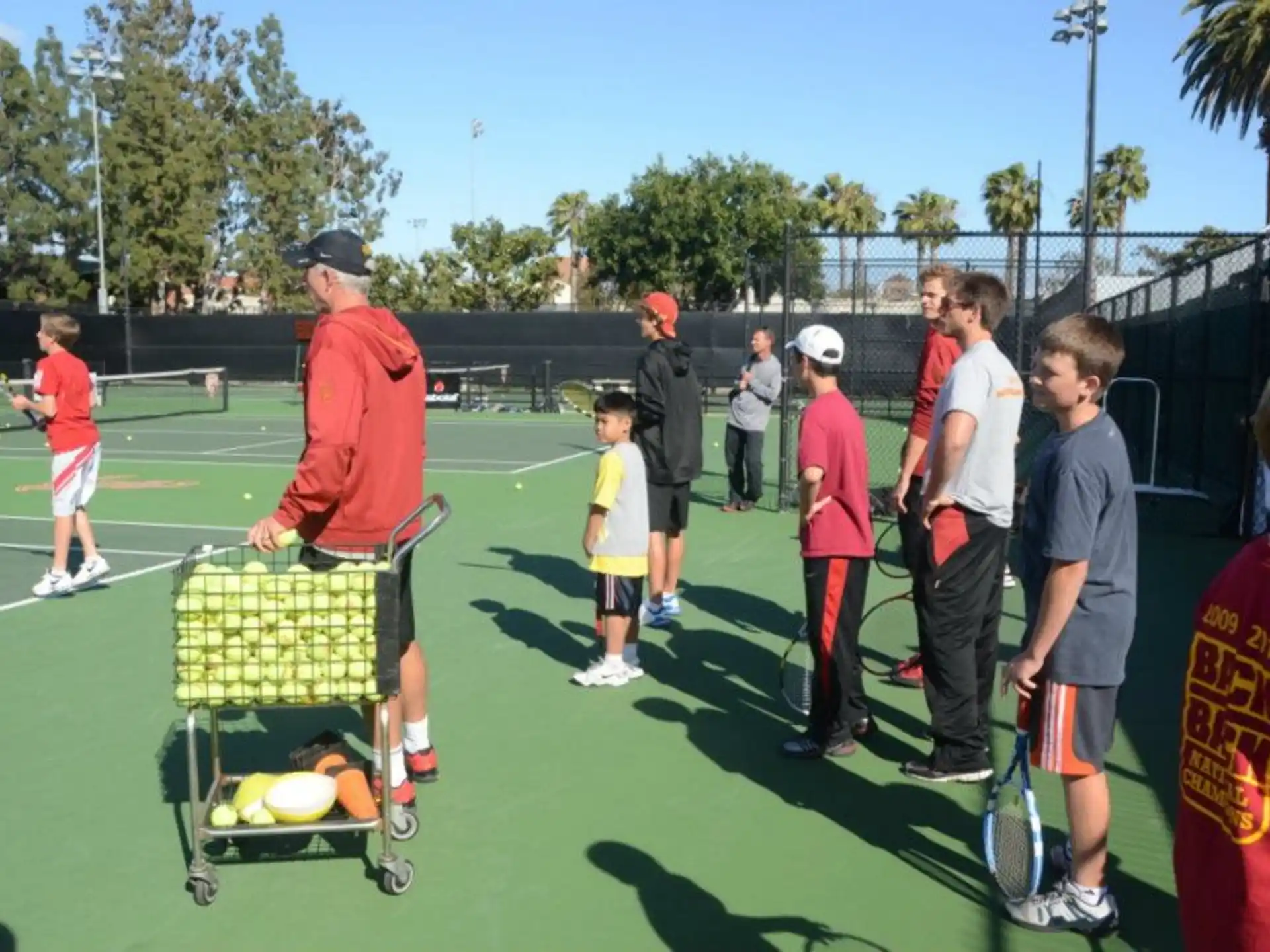 a group of people stand around a tennis court