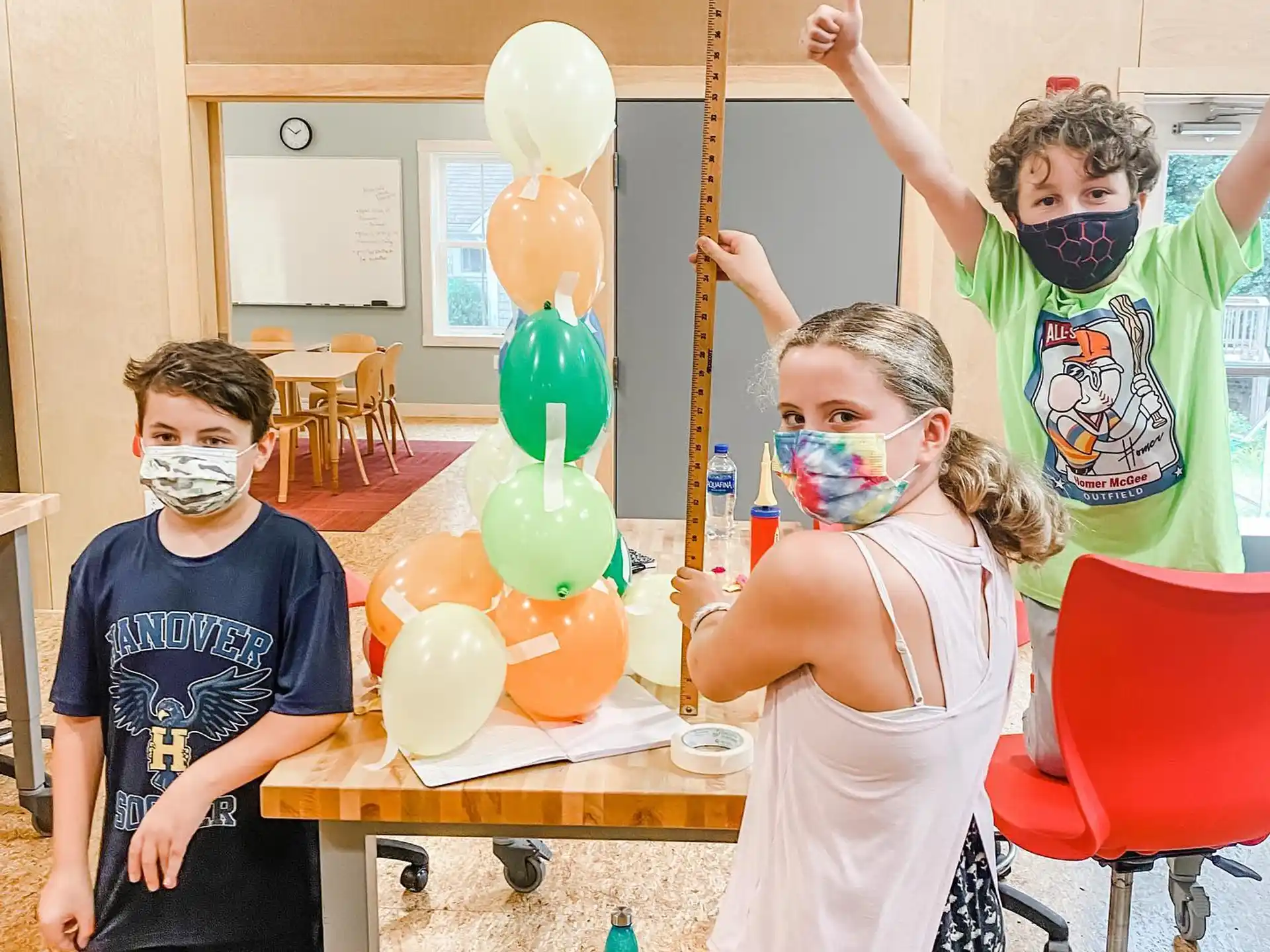 a group of kids wearing masks and holding balloons