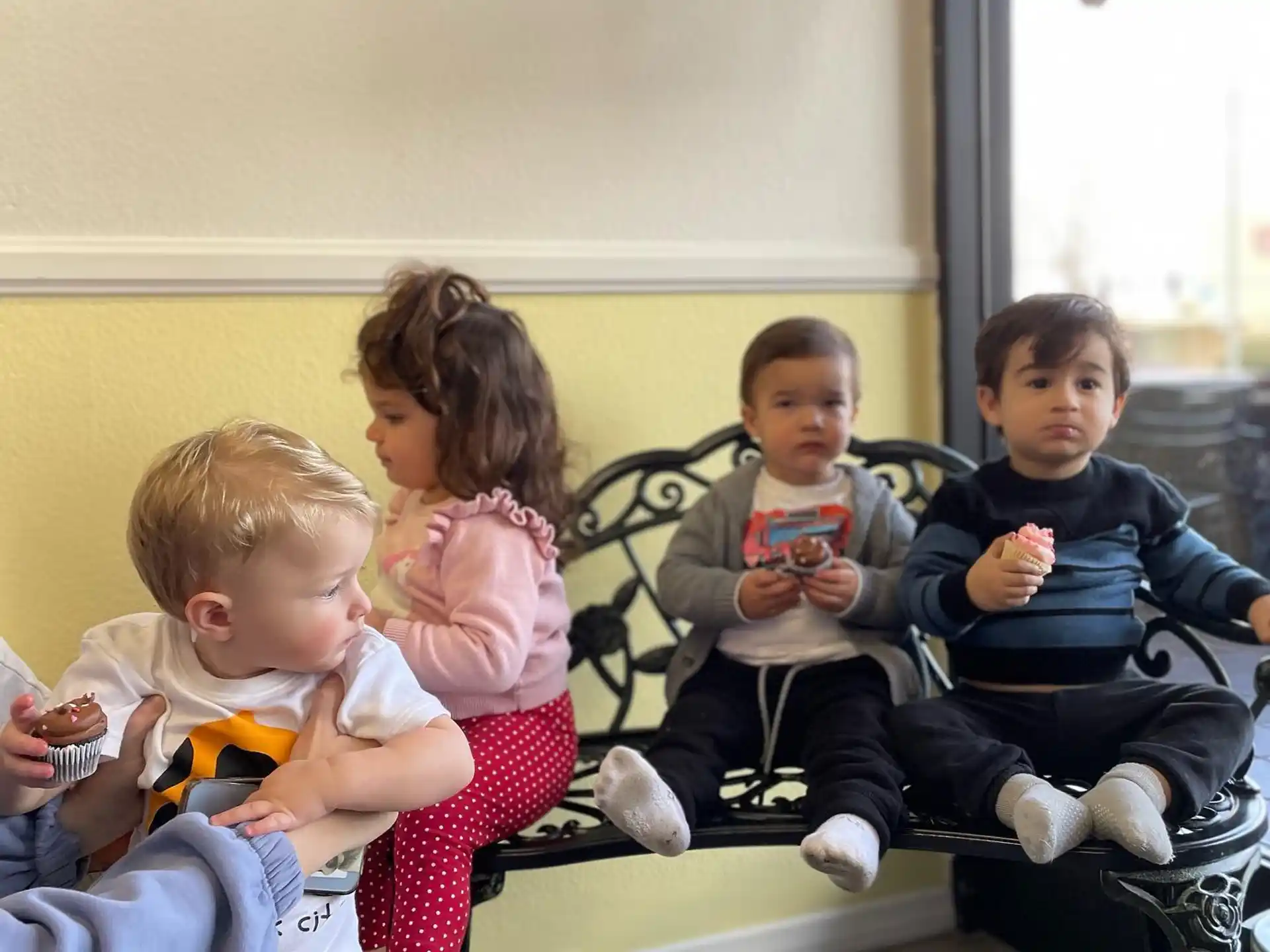 a group of children sitting on a bench eating