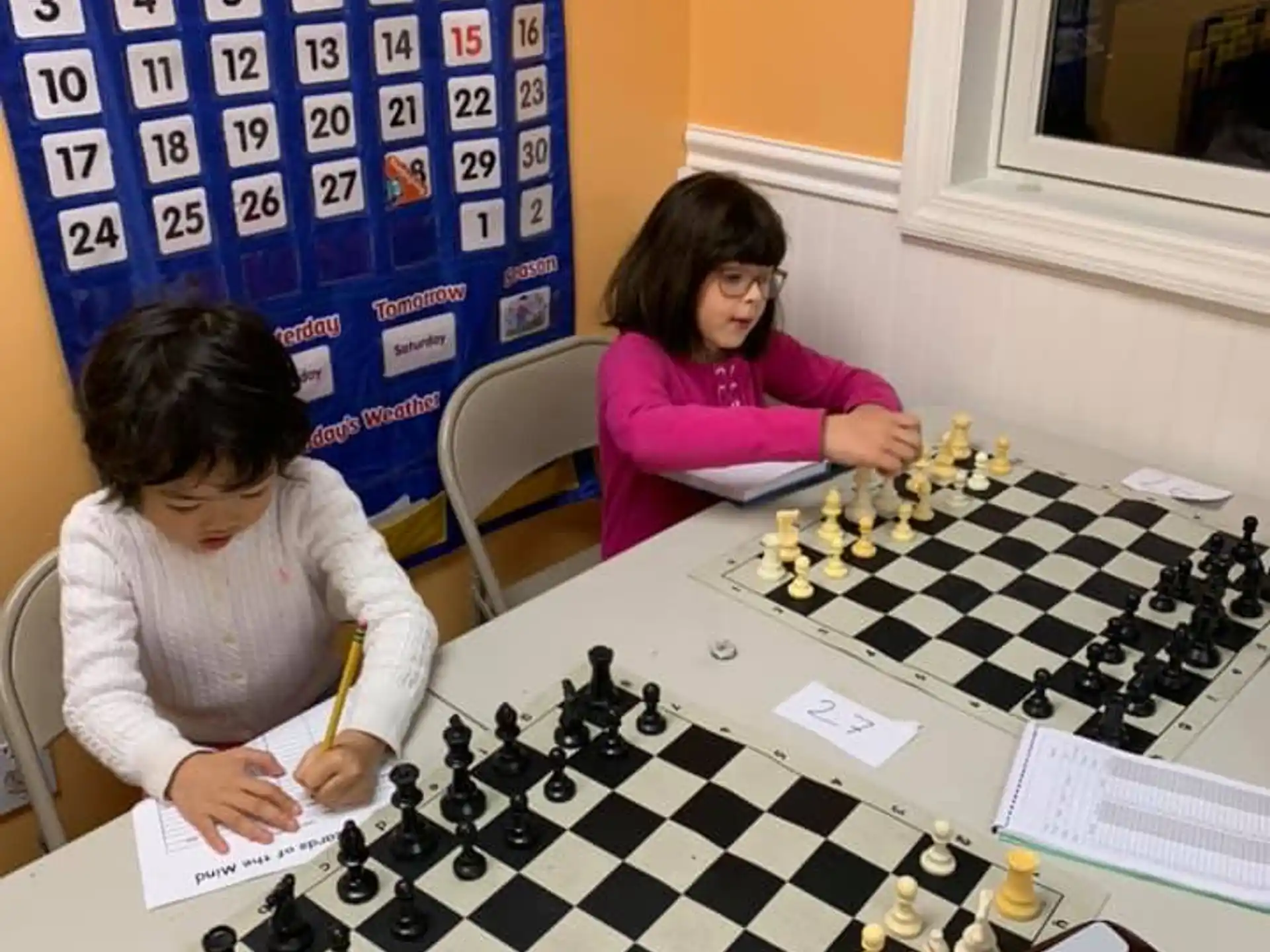 a couple of women sitting at a table with a board game