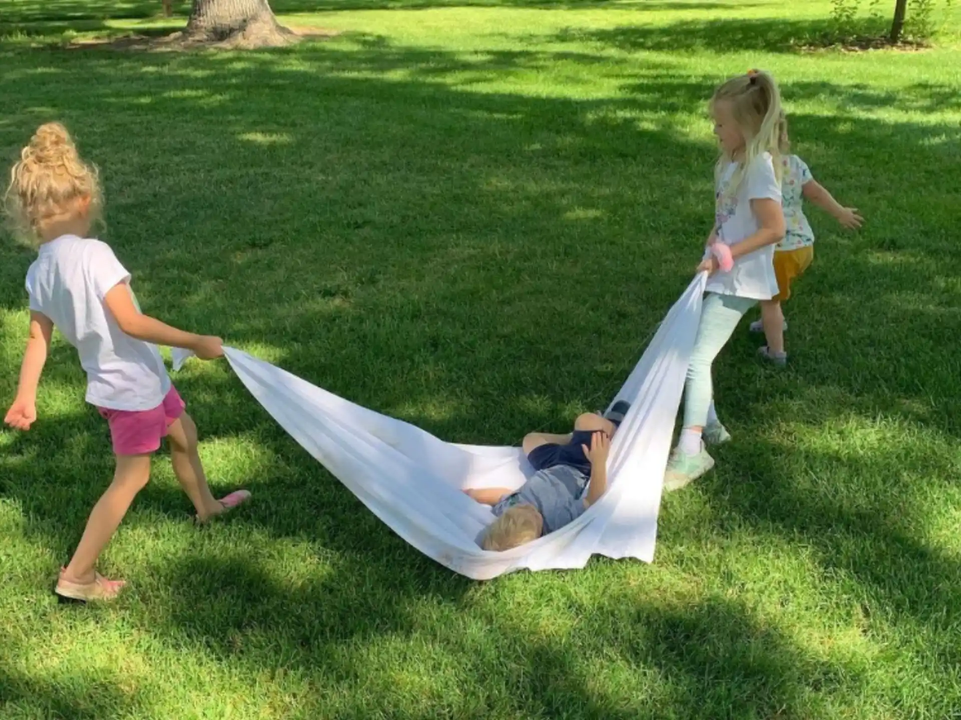 a group of children playing on a blanket in the grass