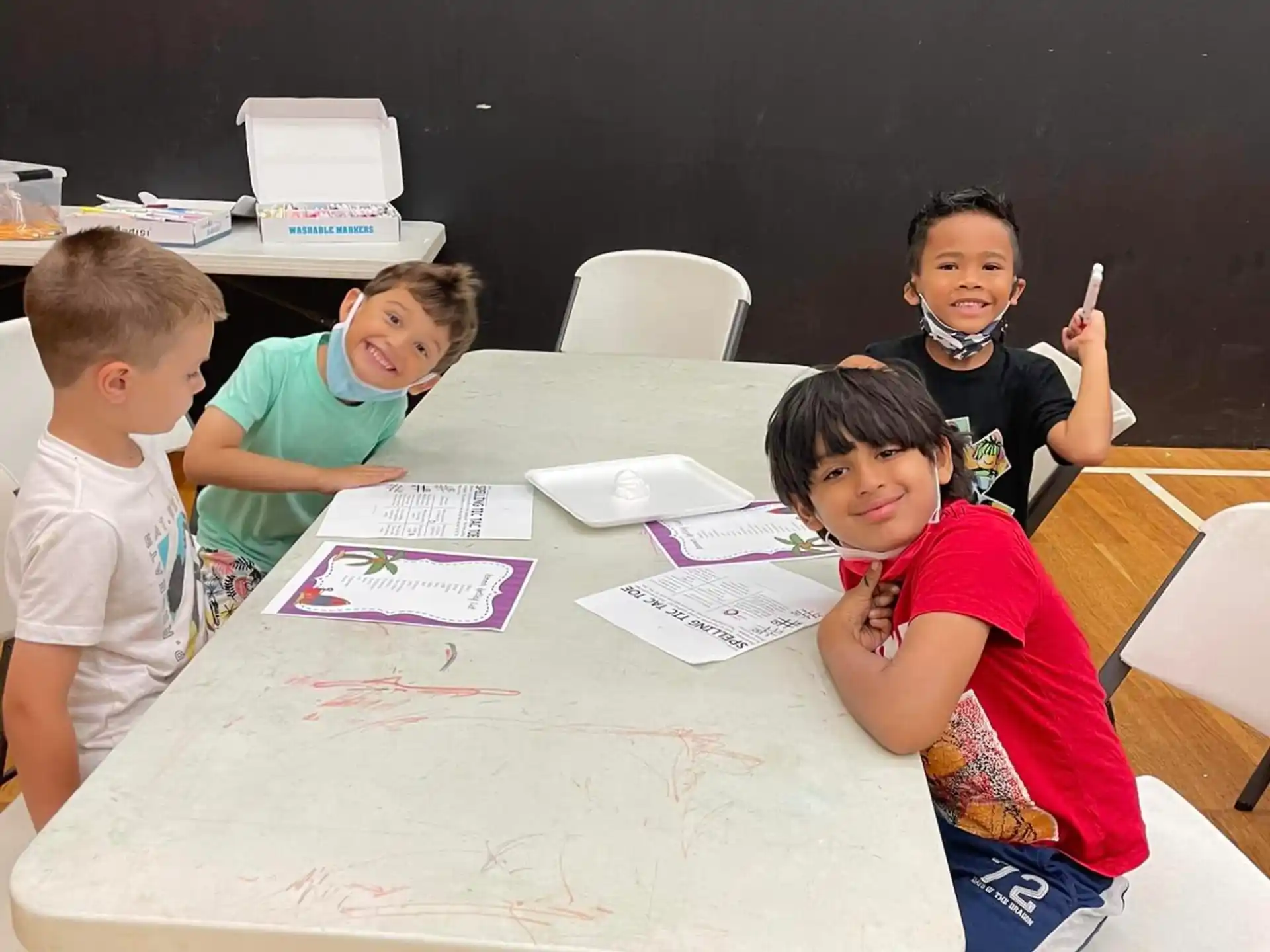 a group of children sitting at a table with paper on it
