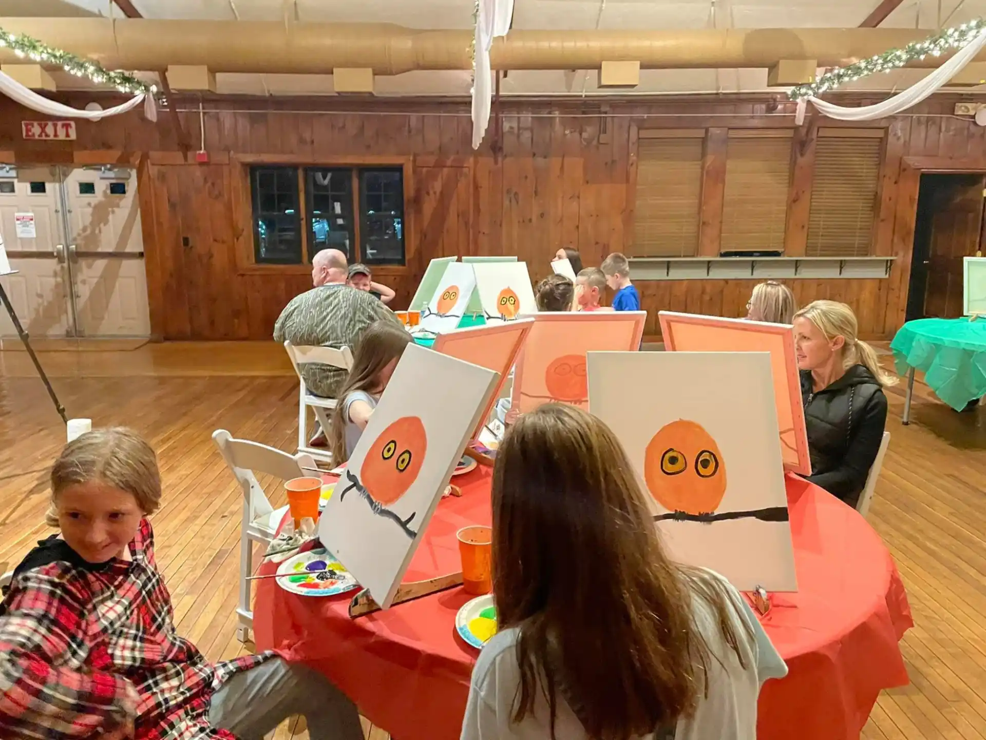 a group of people sitting at a table with a large red tablecloth