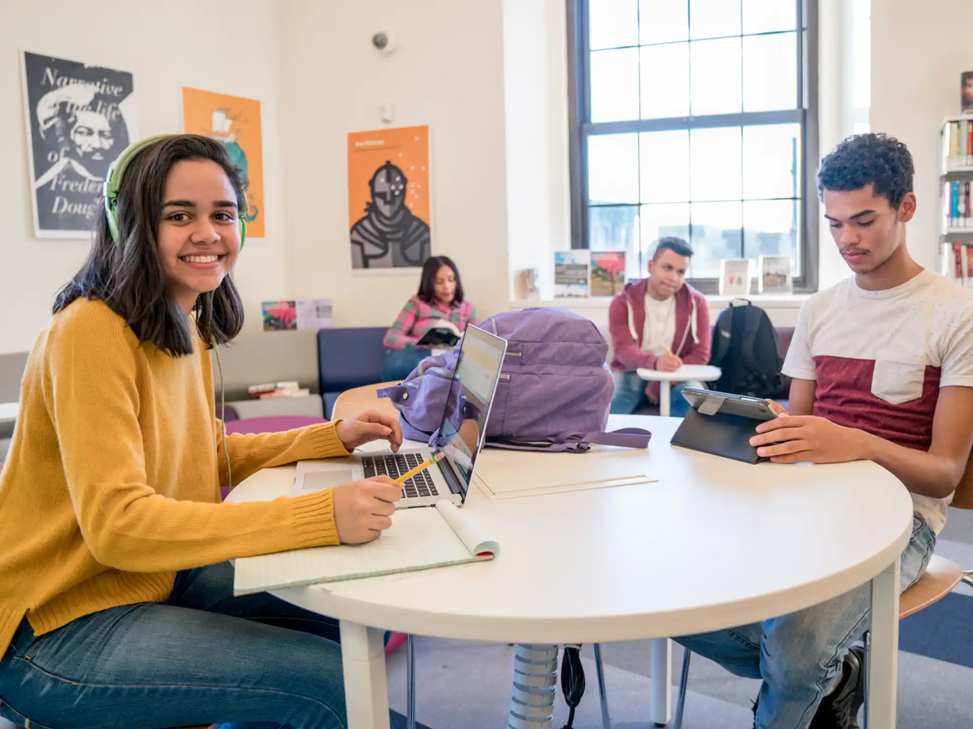 a group of people sitting at a table with laptops