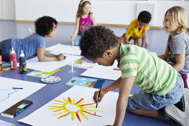 a group of children sitting around a table painting